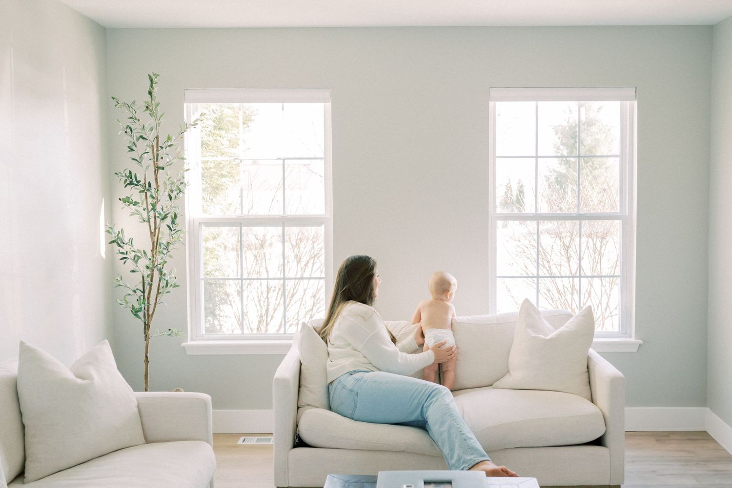Natural light streams through windows in a minimalist living room with light blue walls.