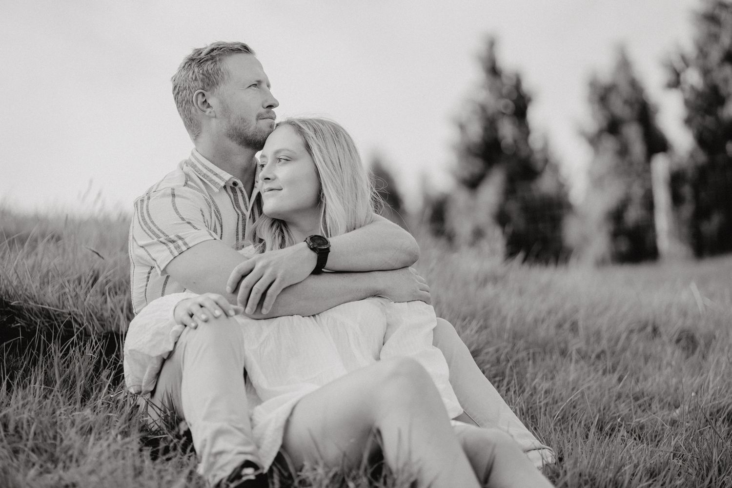 Black and white portrait of couple sharing an intimate moment in a grassy field.