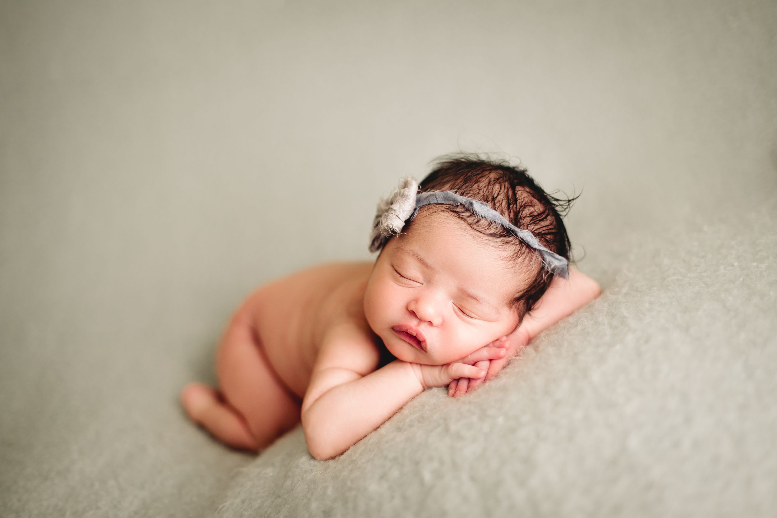 infant posed laying on tummy with chin resting on hands
