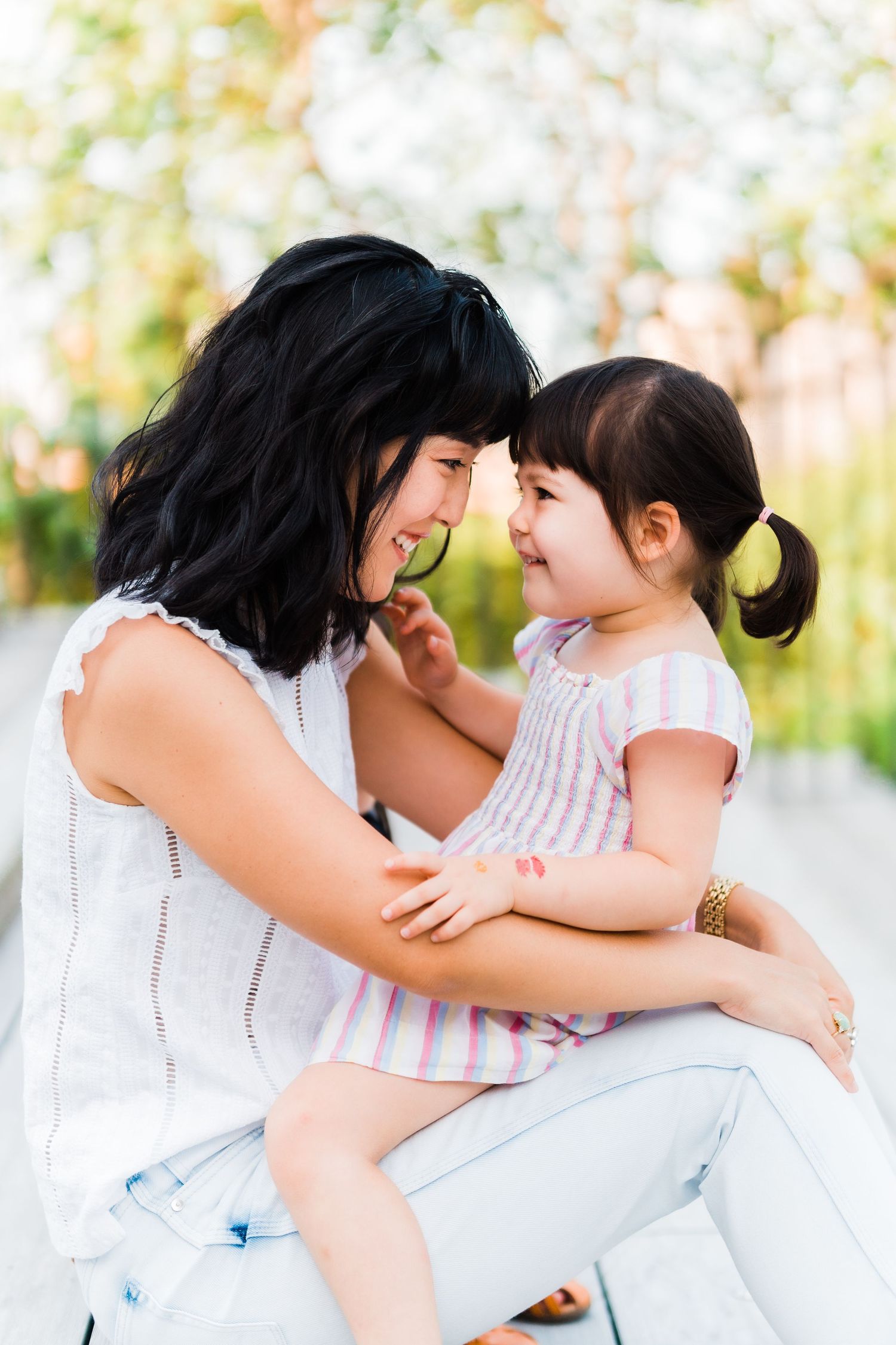 daughter looks into mother's eyes while sitting on her lap