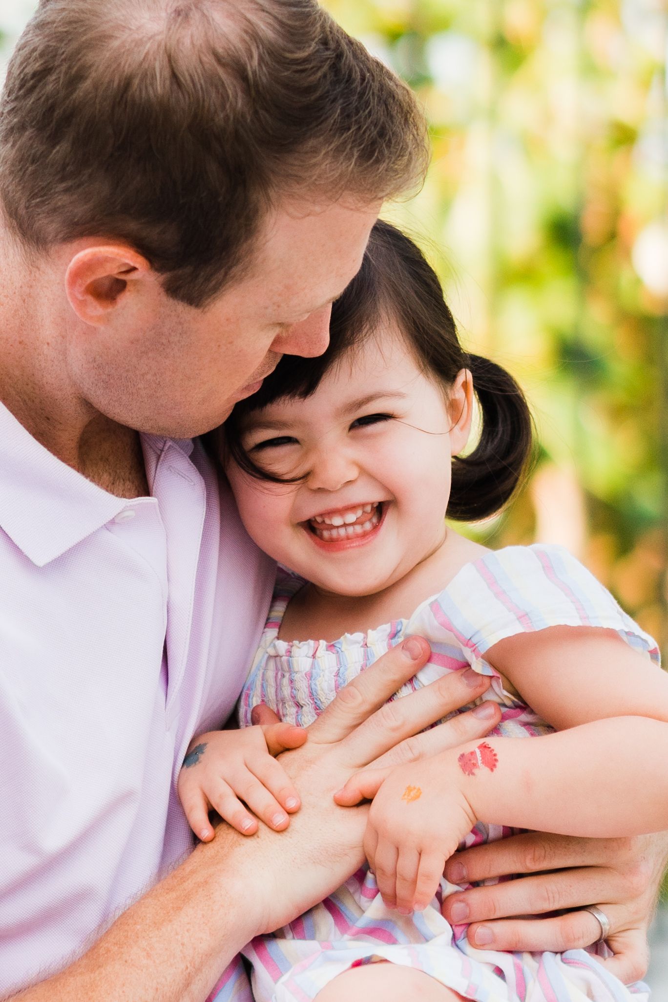 father tickles her daughter and she looks into the camera