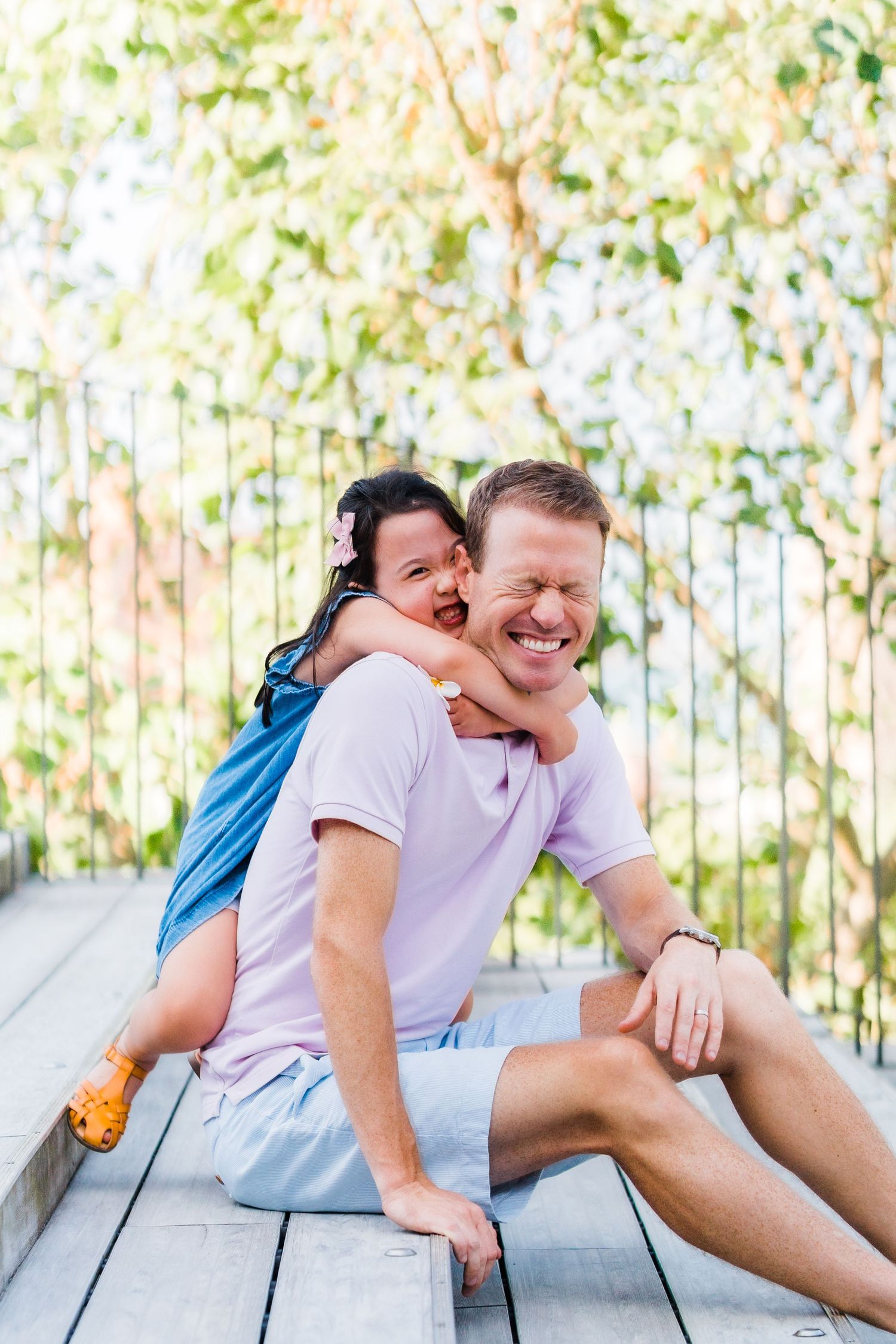 Playful moment captured on wooden deck with natural bokeh background.