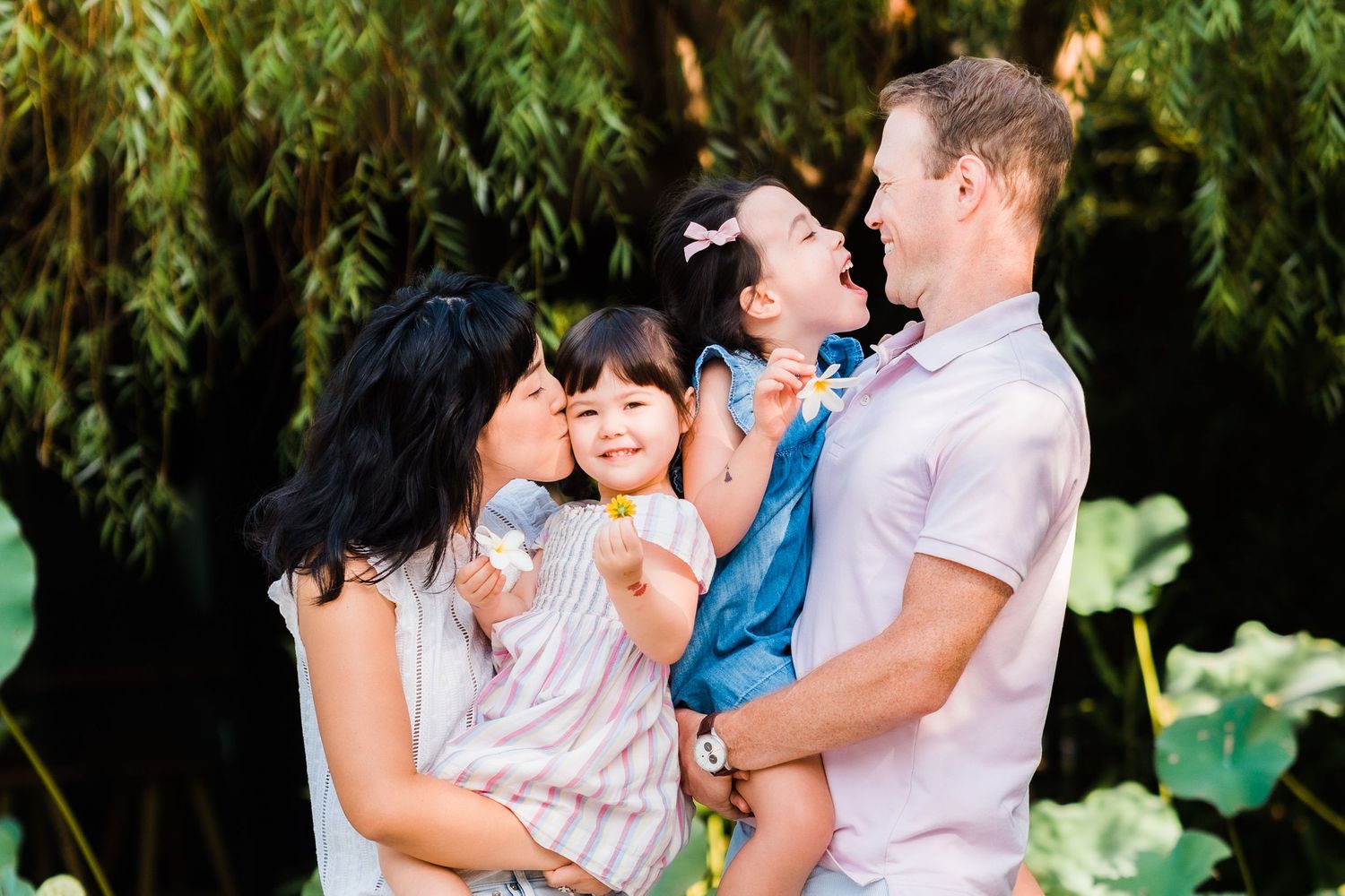family kissing and laughing in front of lily flowers in taipei