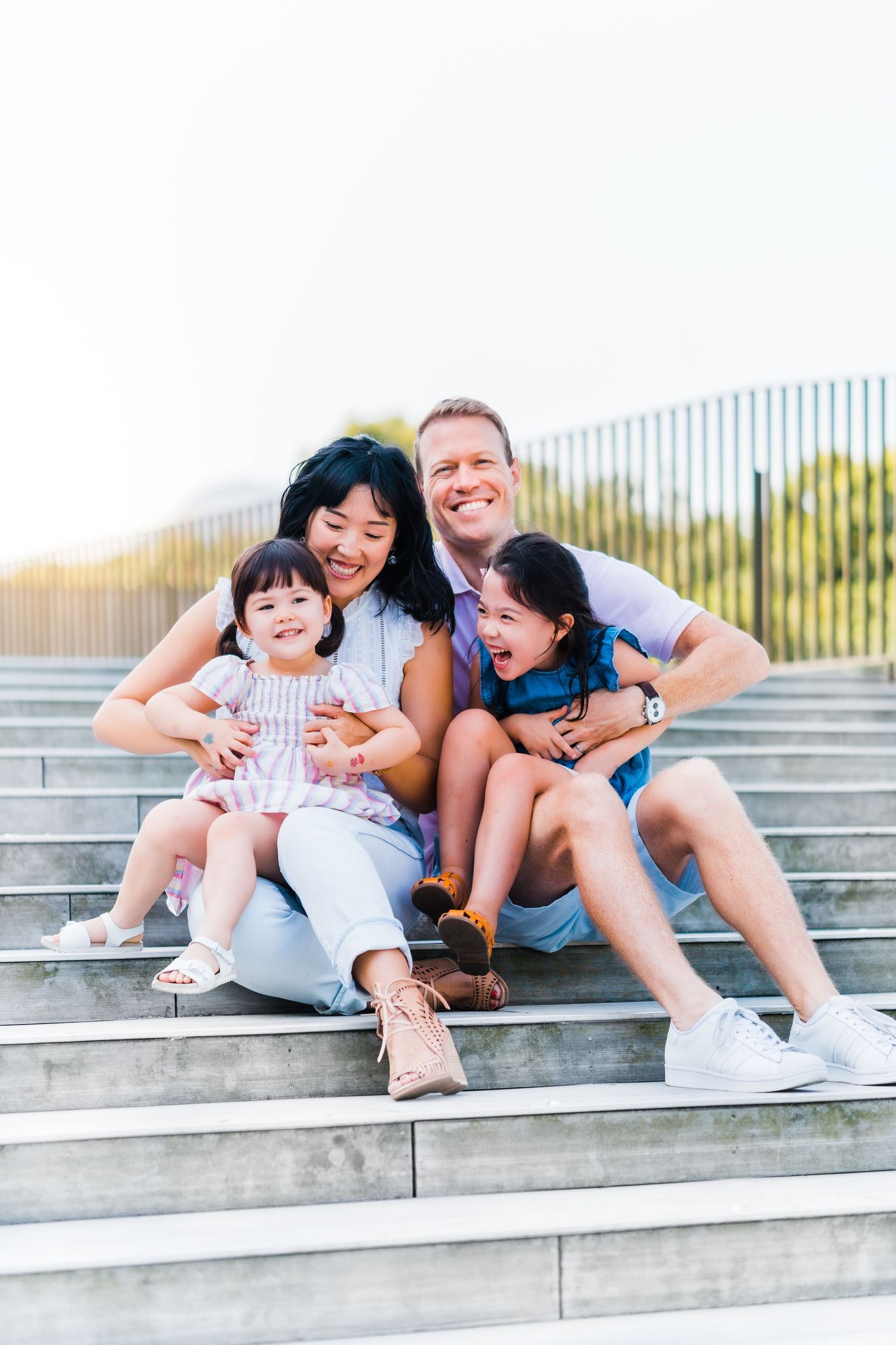 Family sitting together on concrete steps sharing joyful expressions.