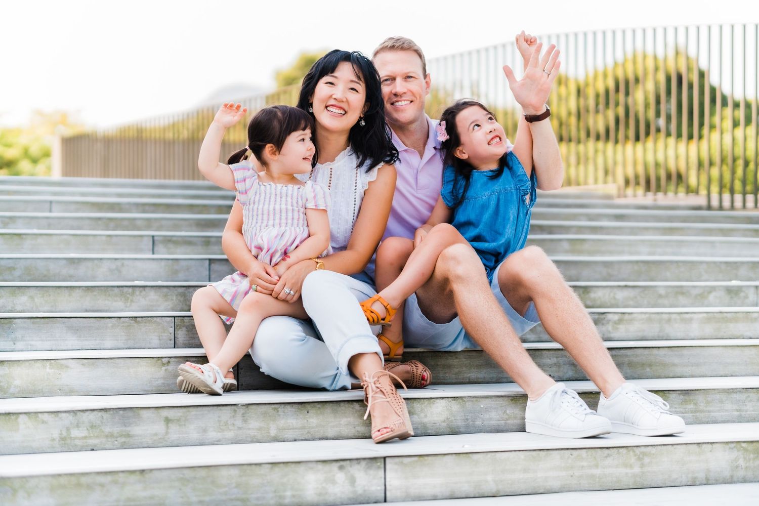 two sisters excitingly raising their hands while sitting in their parents' laps