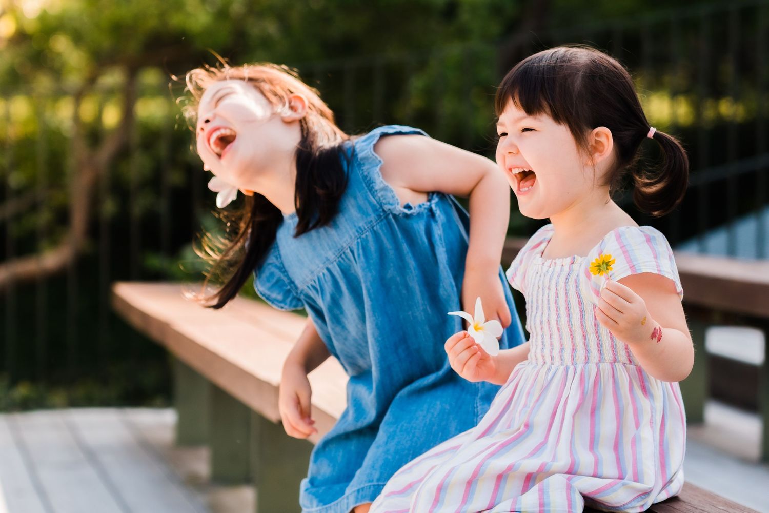 two sisters hold orchid flowers while laughing really hard