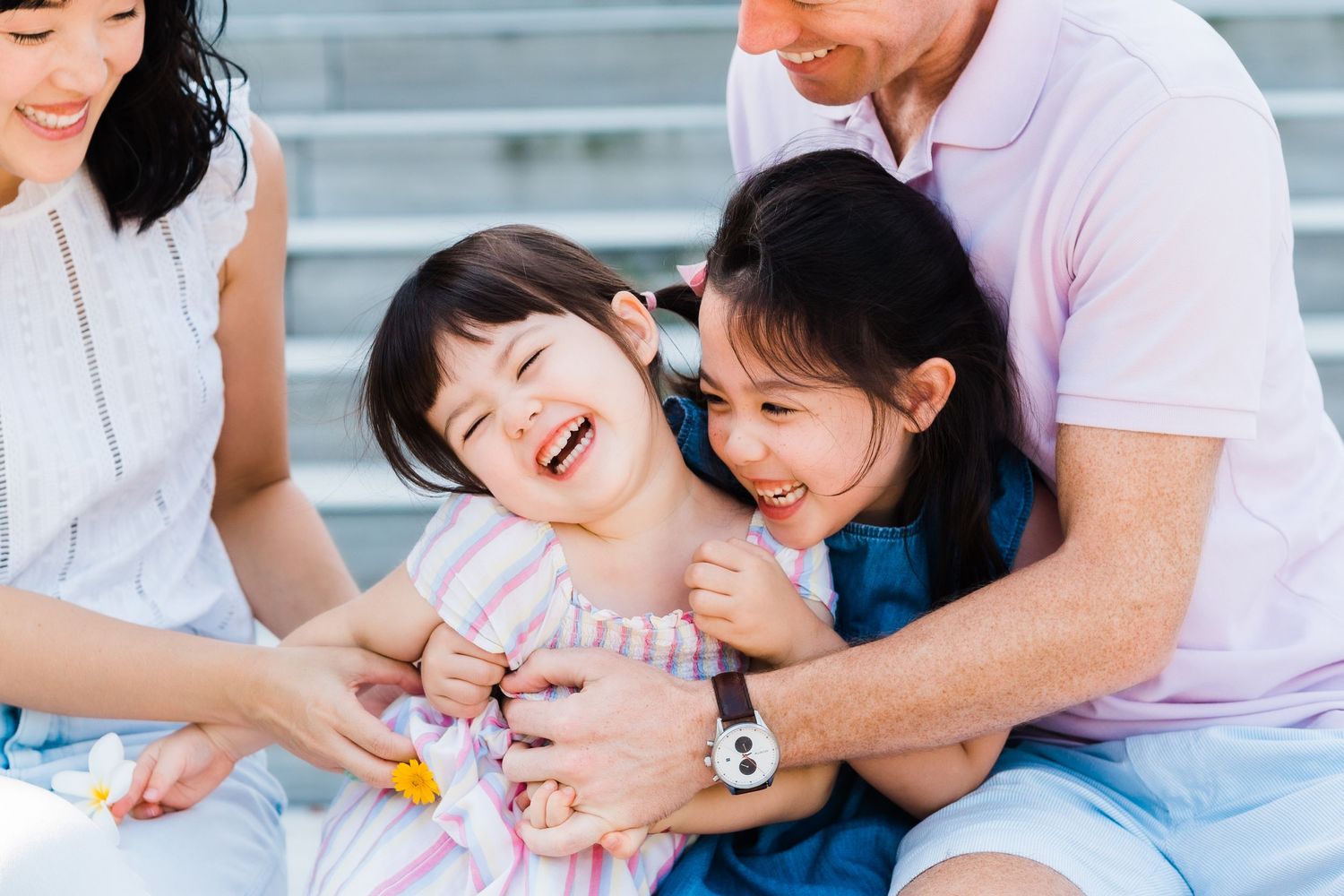 two mixed-race sisters giggling in a tickle fight between their parents
