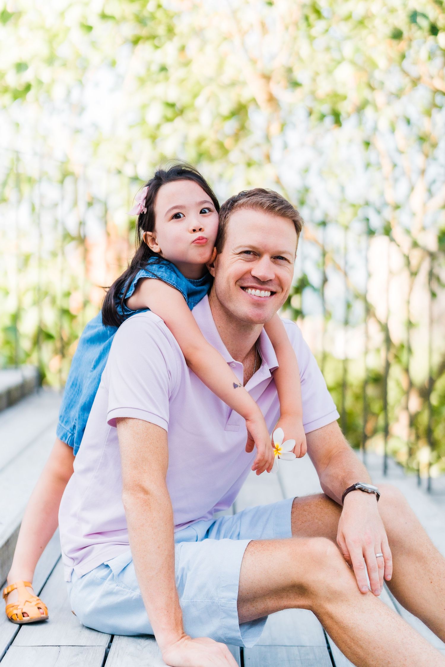 Sweet candid moment shared on wooden deck with sunny garden backdrop.