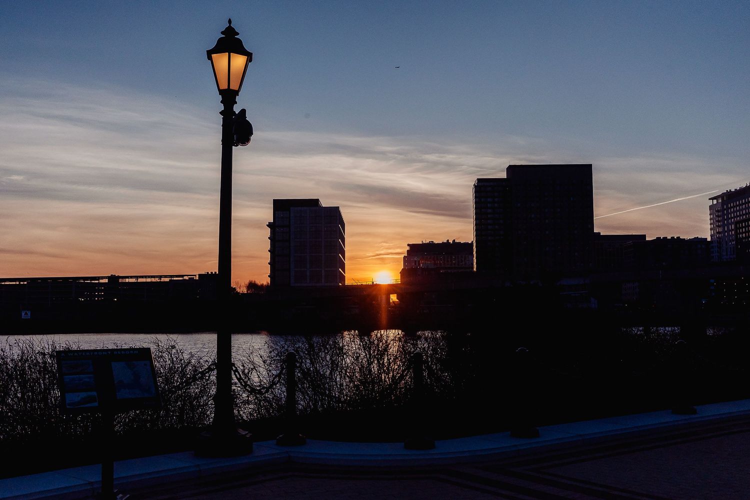 Silhouette of vintage lamppost against sunset skyline in Boston.