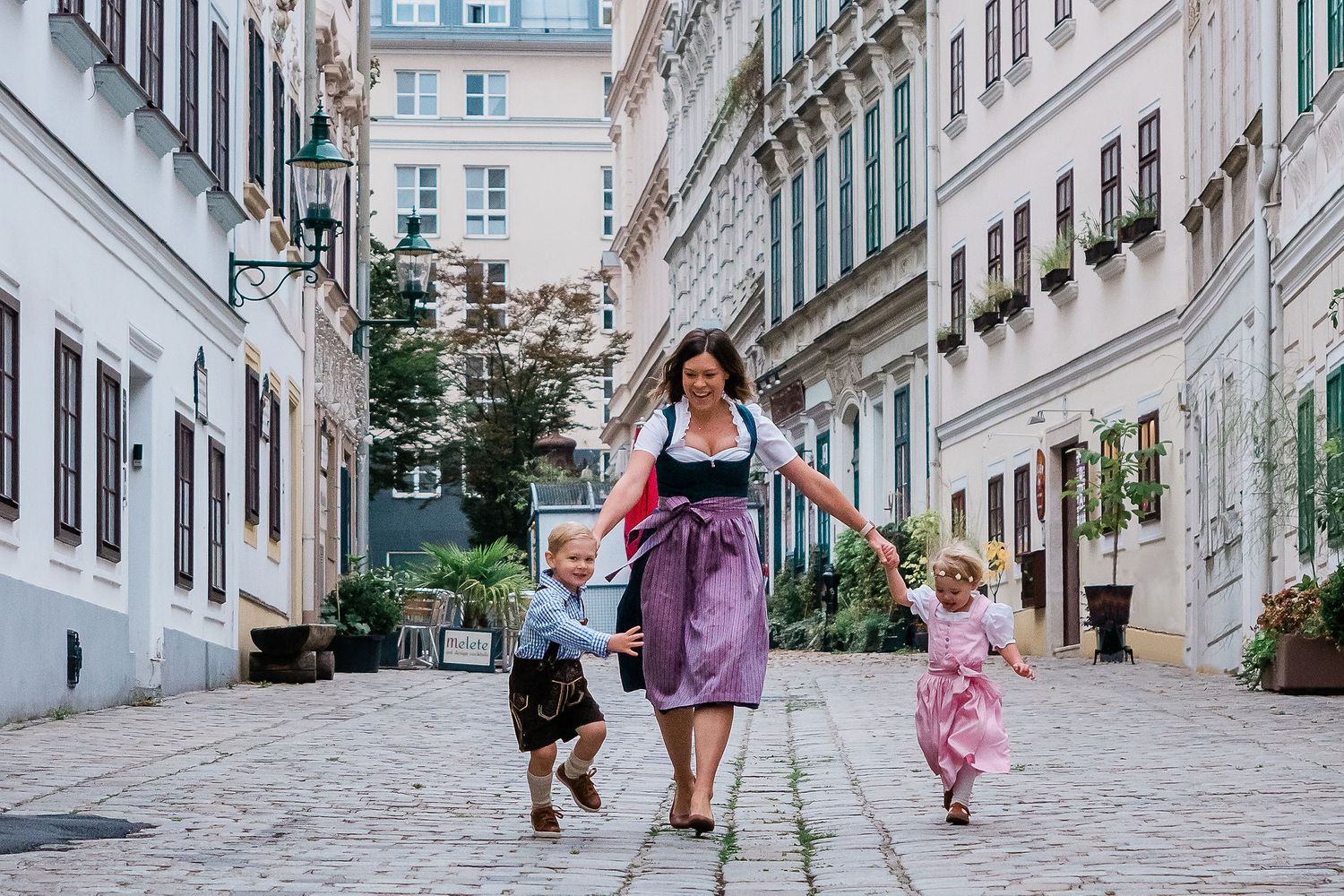 Mother running with kids in Spittelberggasse 7th district Vienna wearing traditional outfit