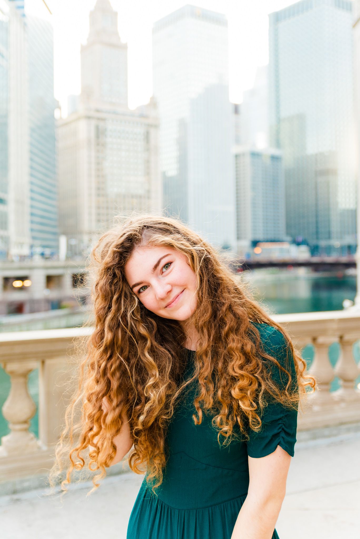 photo of Alana Lindenfeld, curly hair in teal jumpsuit in front of Chicago Riverwalk