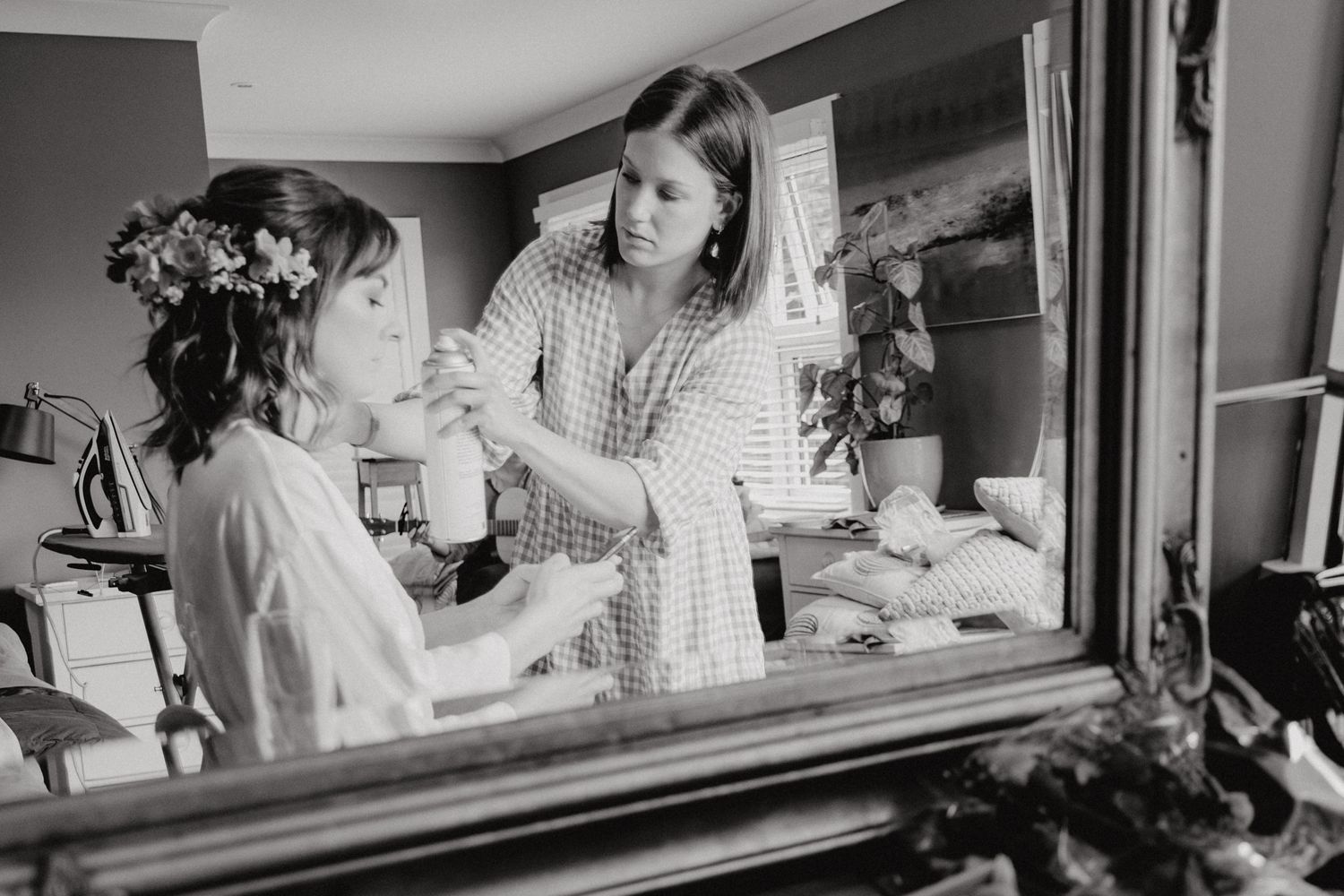 Black and white image of wedding day preparations reflected in mirror.