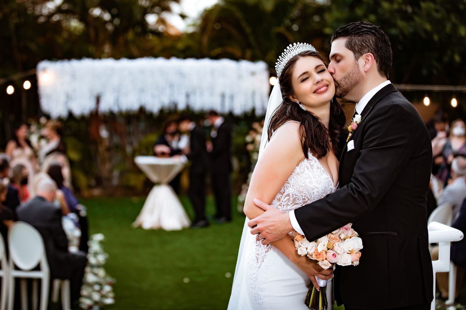 Candid wedding moment with couple embracing outdoors during sunset ceremony.