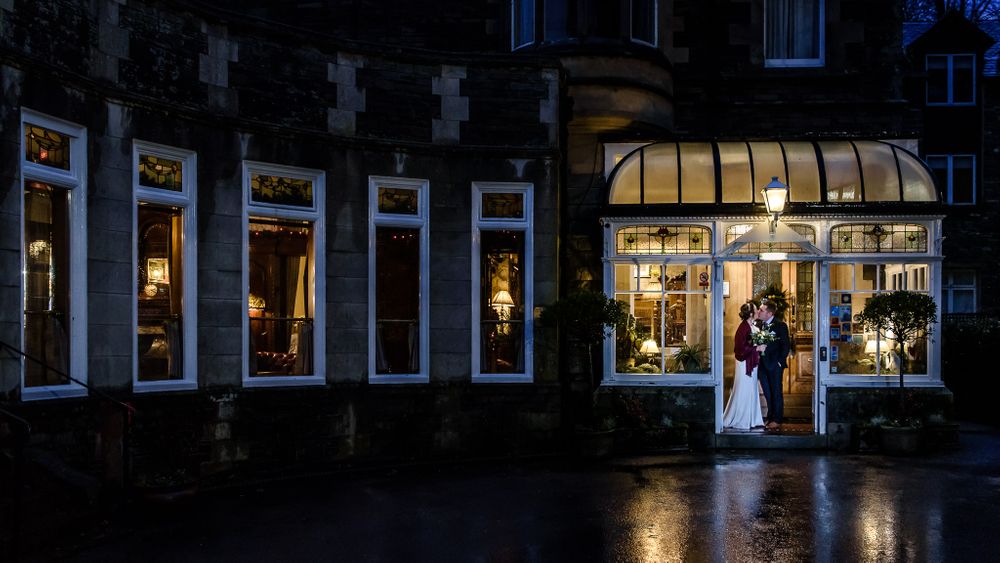 Newlywedsstanding under porch on rainy day at Merewood Hotel