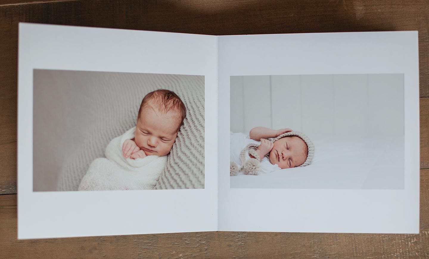 simple newborn photography album opened on a wood table