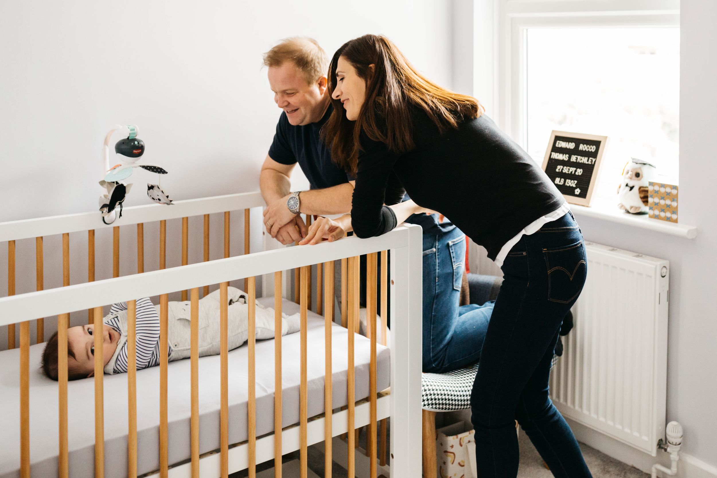 parents looking down at baby laying in crib