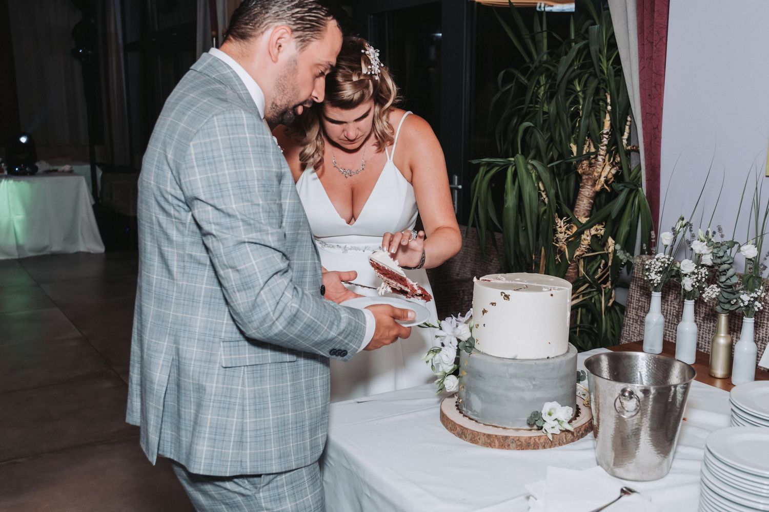 Couple shares an intimate moment while cutting their elegant white wedding cake.