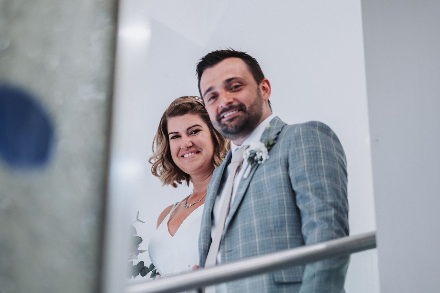 Candid portrait of newlywed couple smiling on modern balcony.