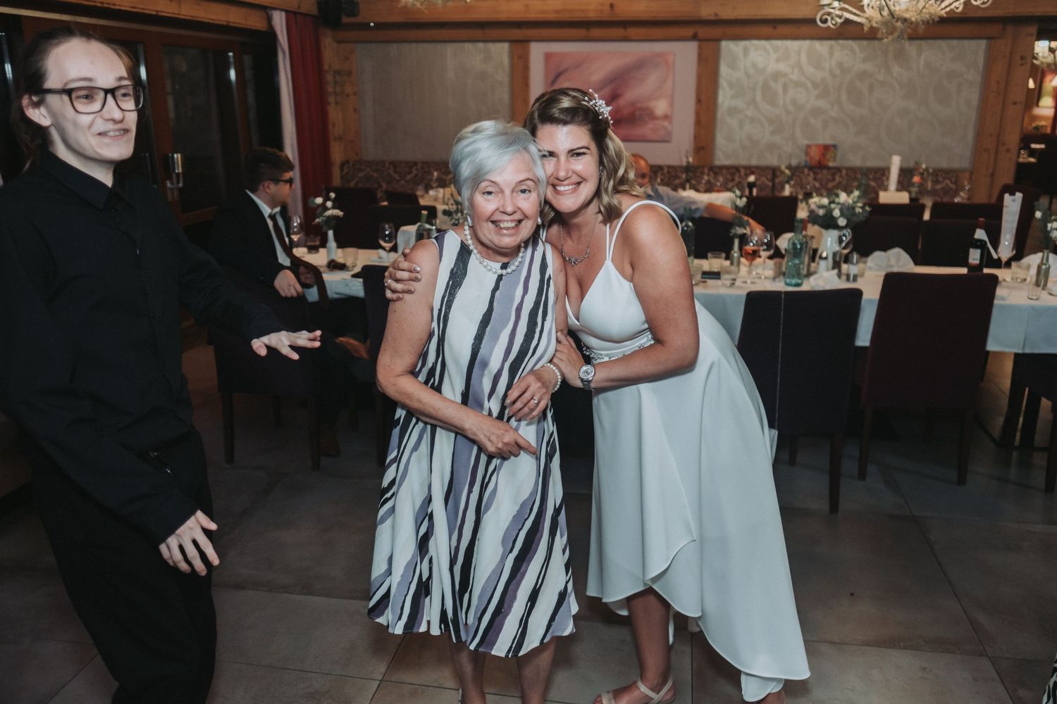 Wedding reception guests share a warm embrace in an industrial-style venue setting.