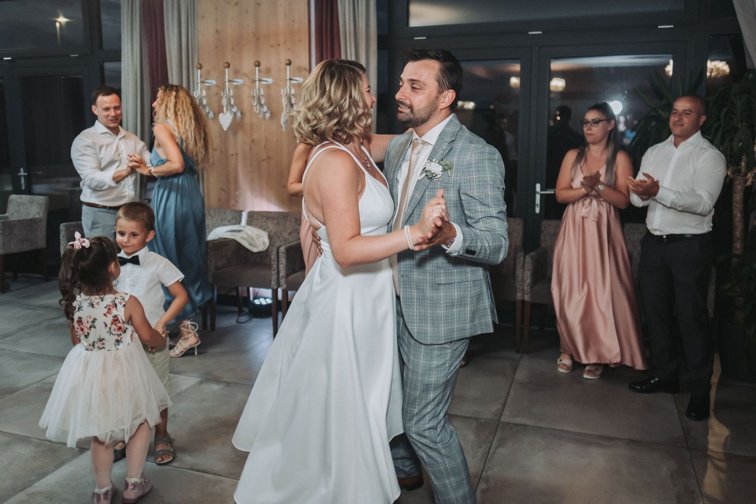 Joyful couples dancing together at a wedding reception with a young flower girl in a tulle dress.