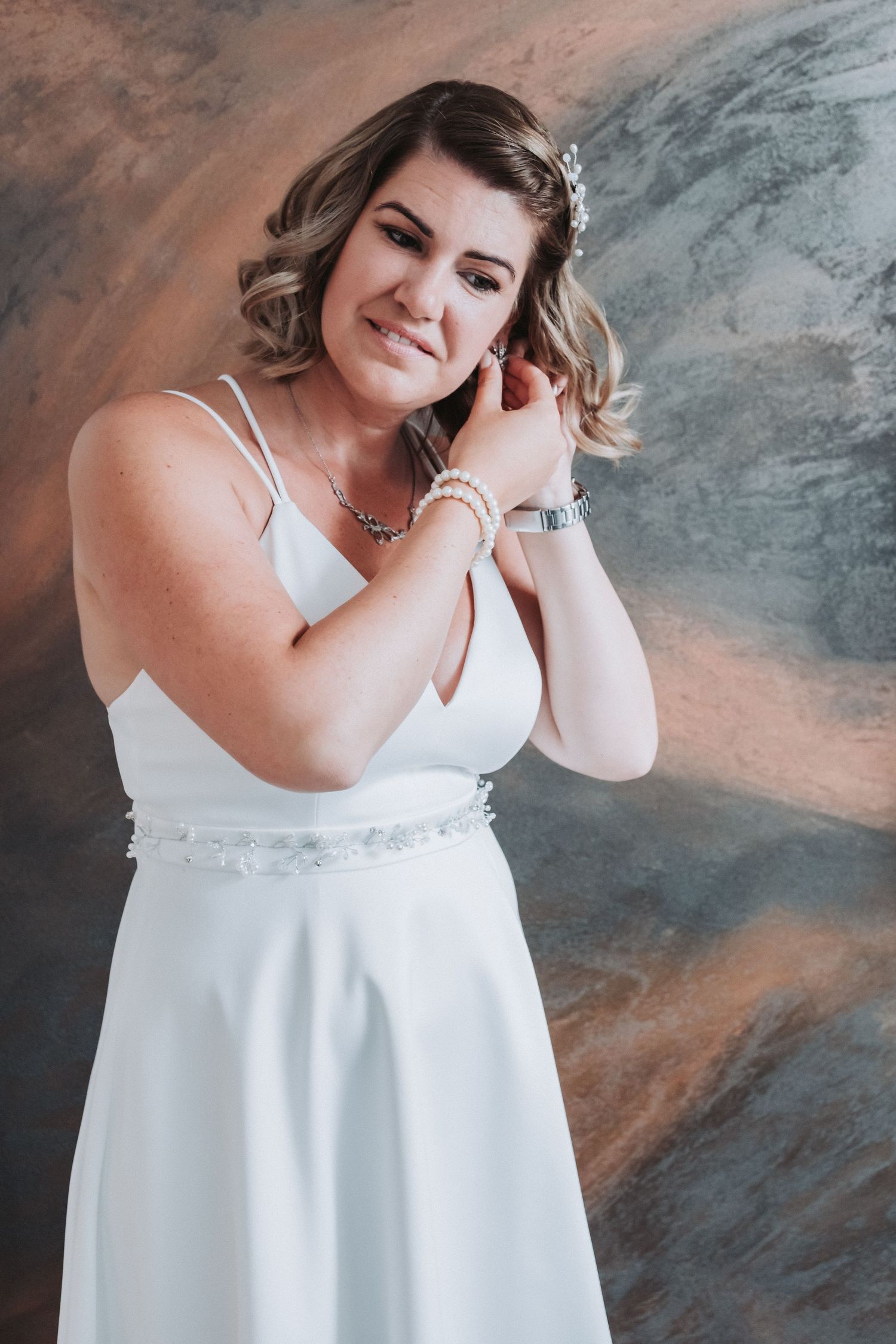 Elegant bride wearing white dress and delicate accessories poses during pre-wedding photoshoot.