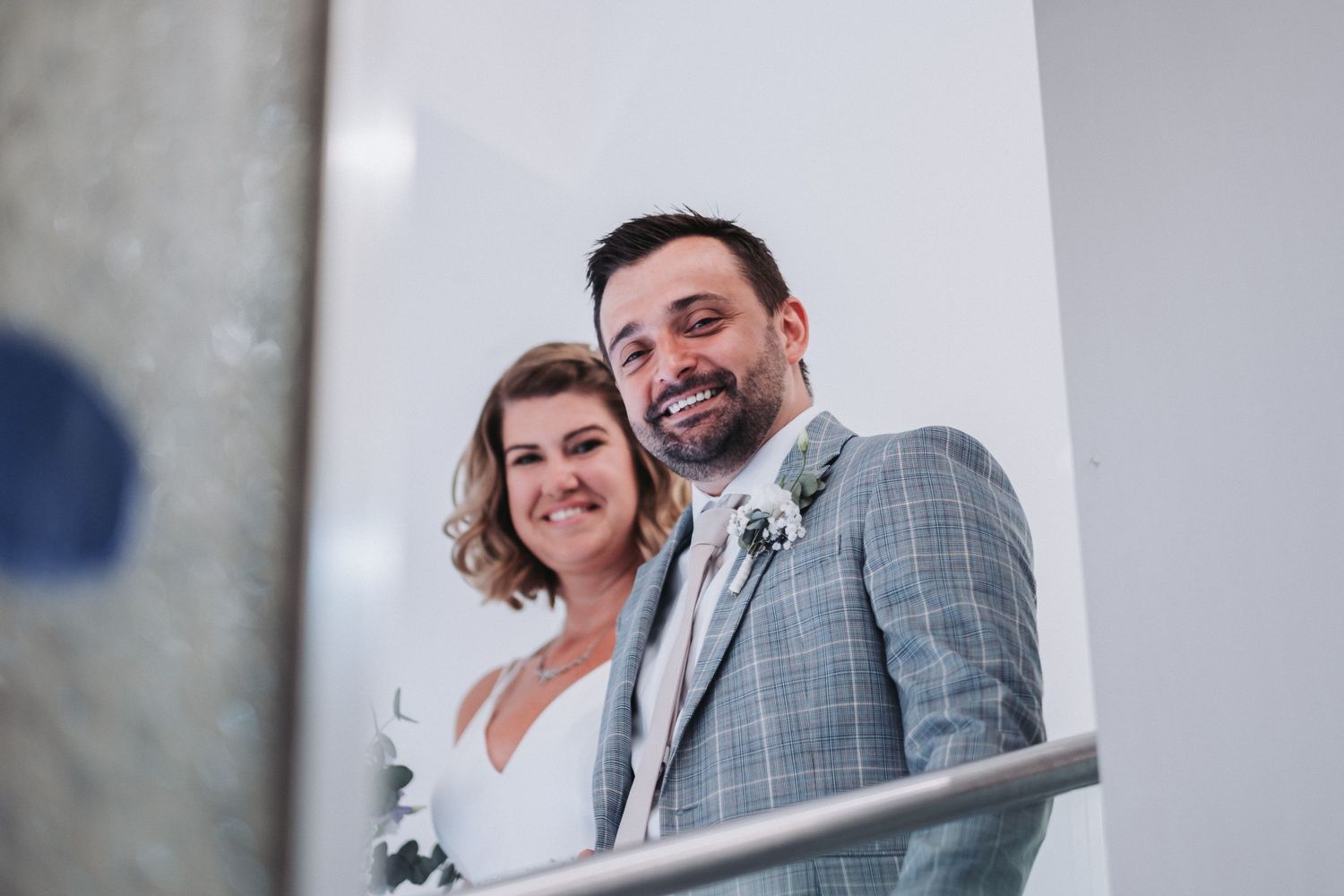 Happy newlyweds pose together on balcony after wedding ceremony.