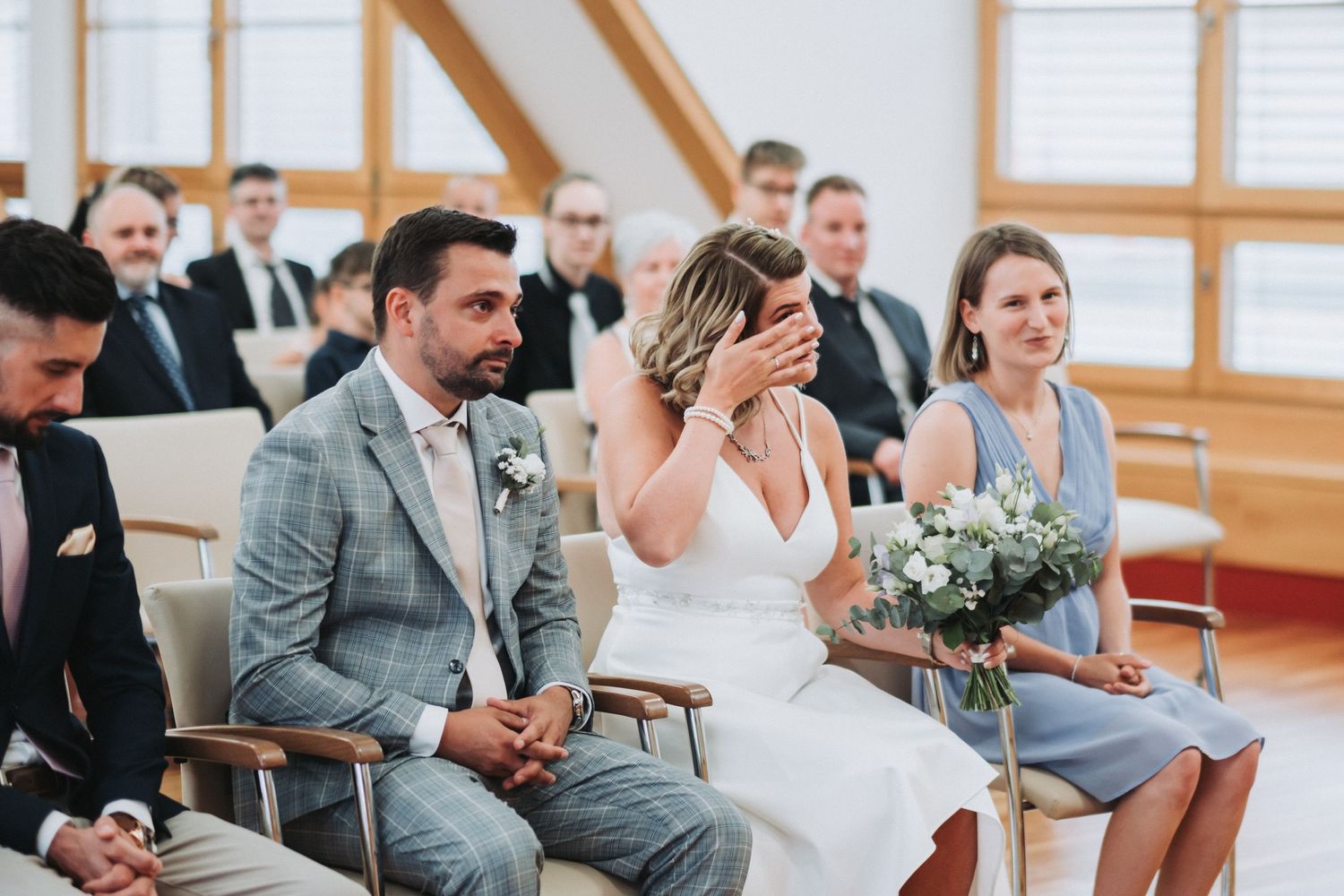 Wedding ceremony in bright indoor venue with wooden beams and natural light.