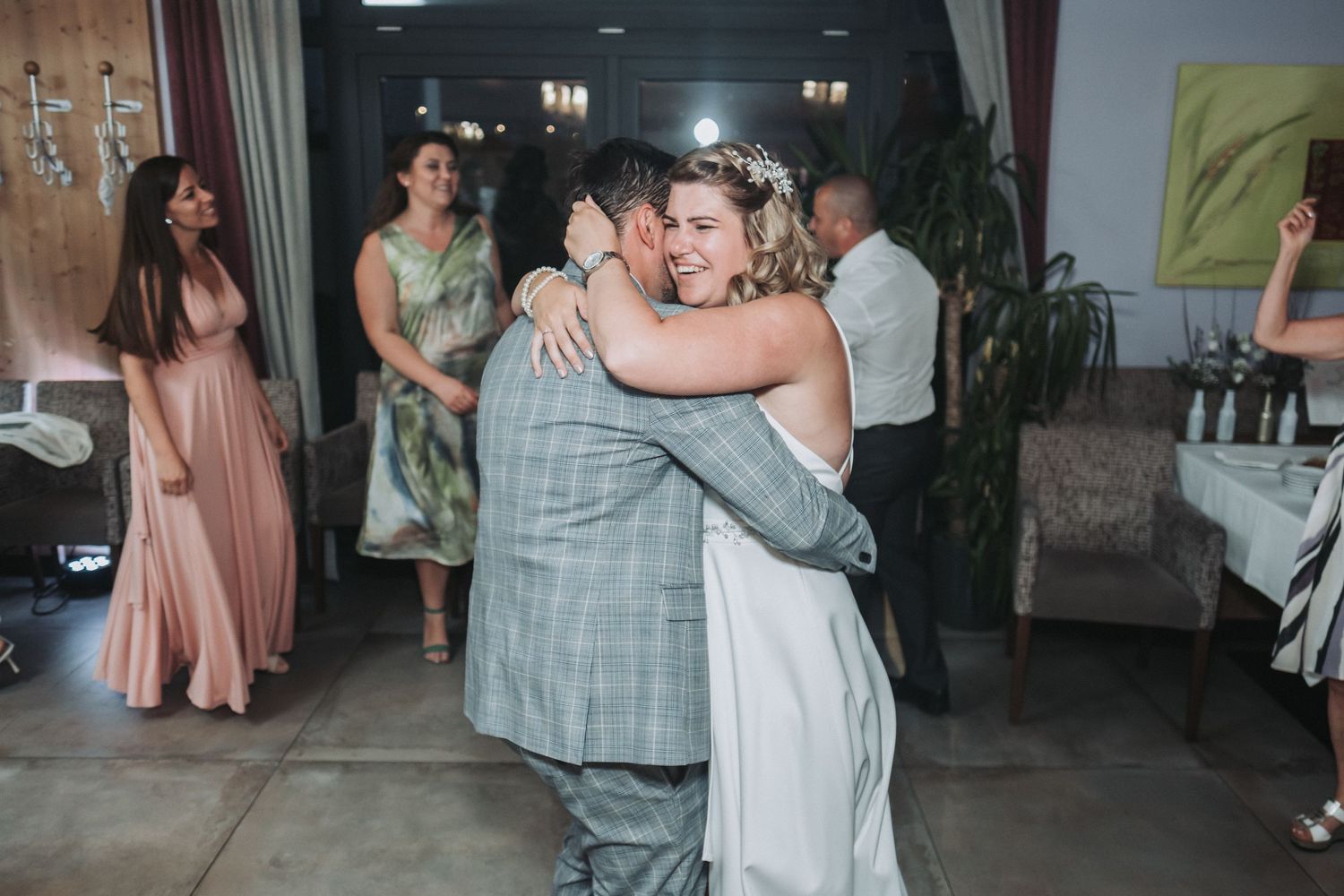 Couple sharing first dance at wedding reception while guests look on.