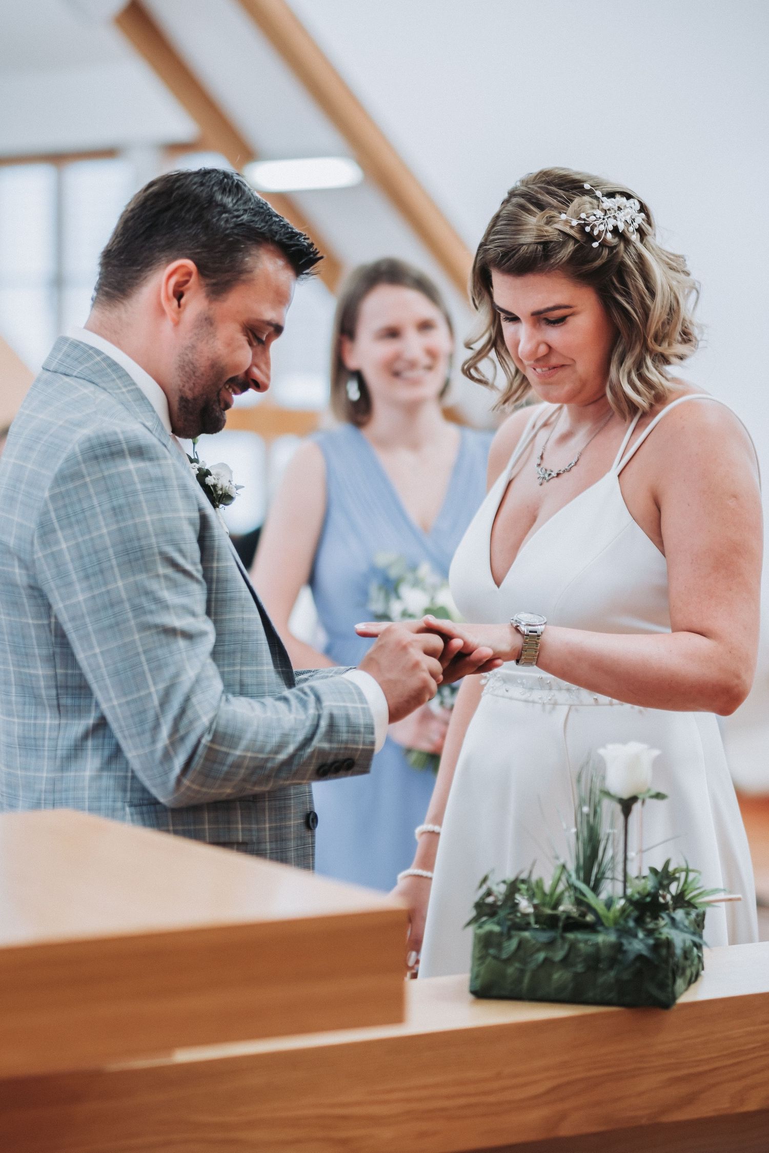 Couple exchanging rings during intimate wedding ceremony with officiant in background.