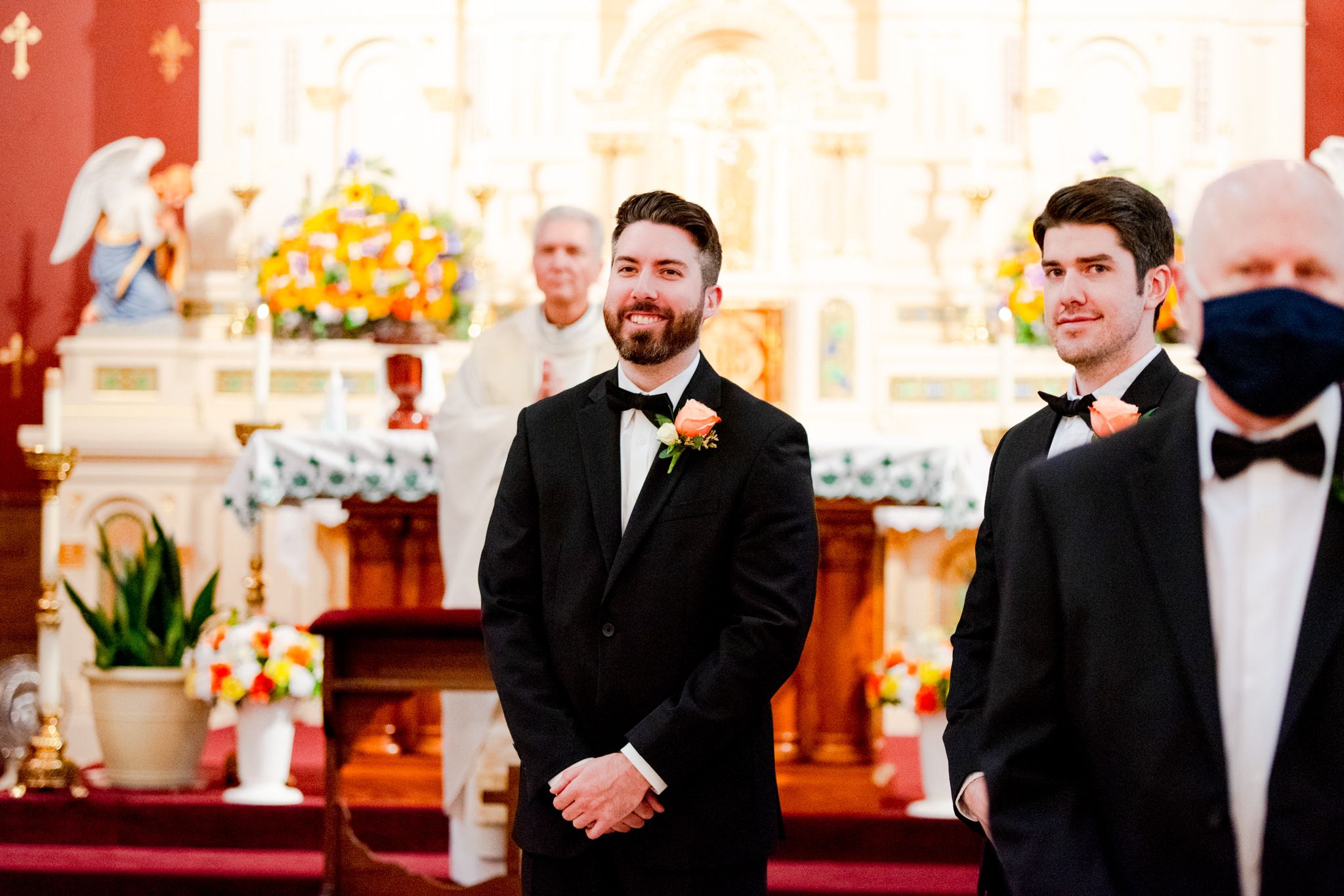 brunette groom and his brother watching the bride walk down the aisle of the church, both smiling at her