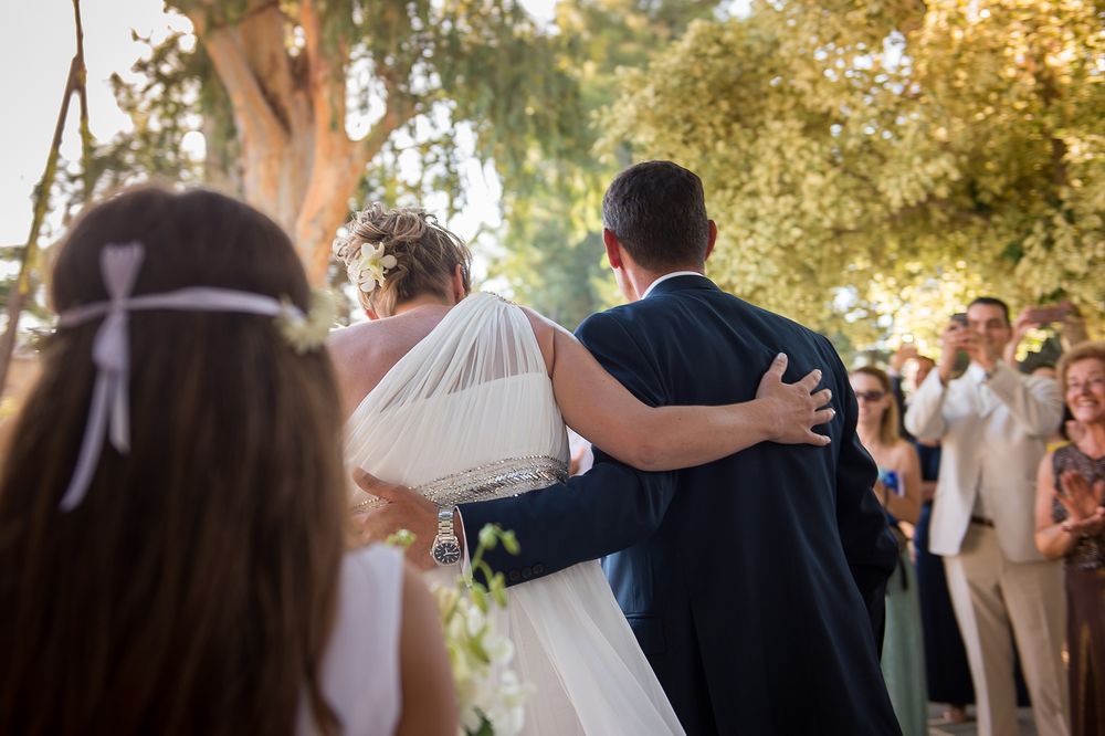 backs of bride and room hugging each other while walking towards the church