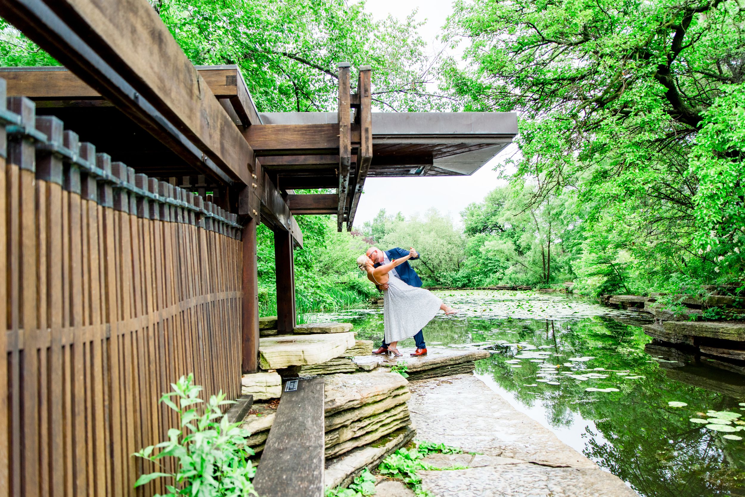 Couple kissing and dipping under trees at Alfred Caldwell Lily Pool Chicago summer elopement