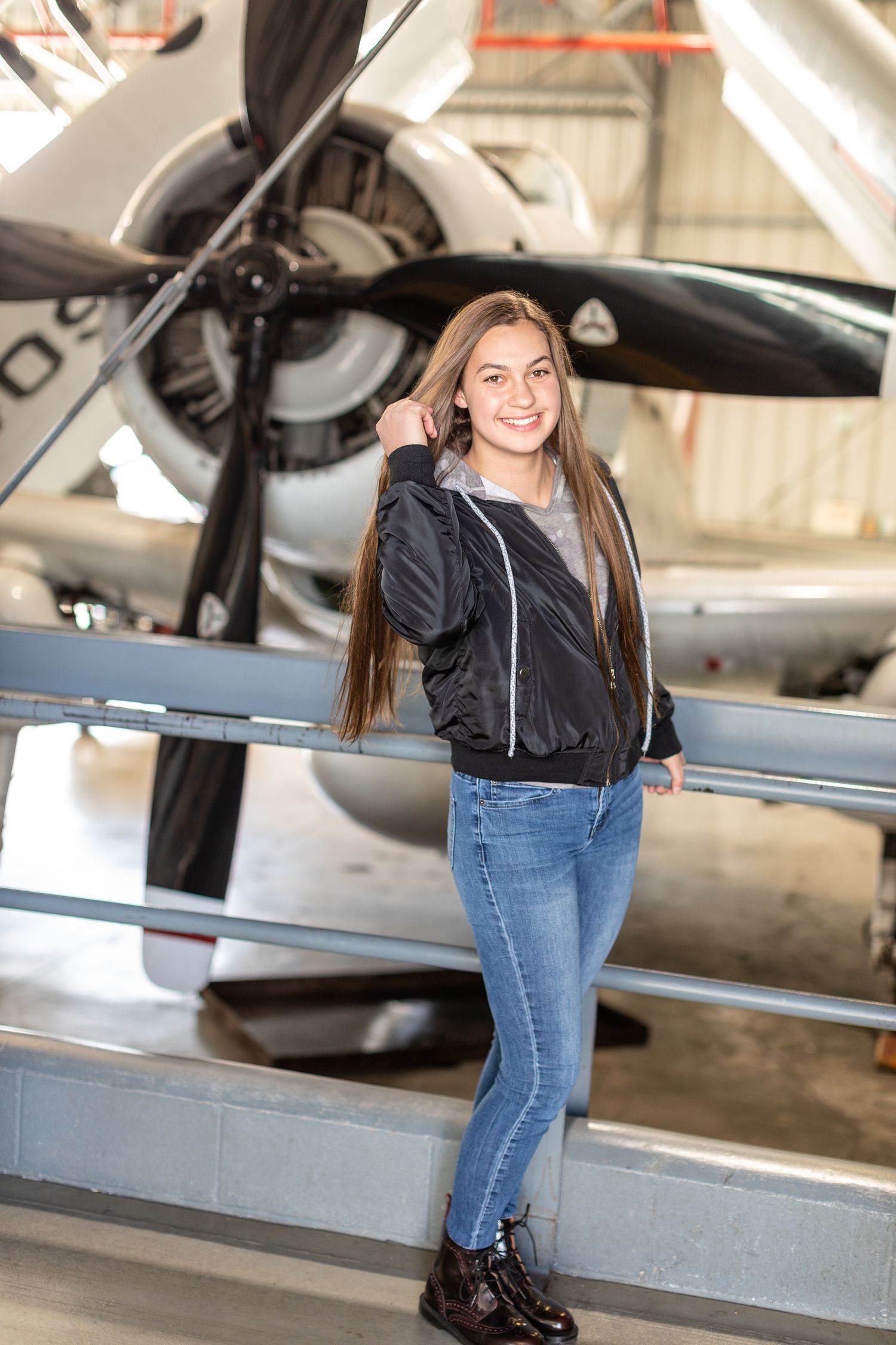 Girl wearing a bomber jacket and Dr. Marten shoes in front of a propeller