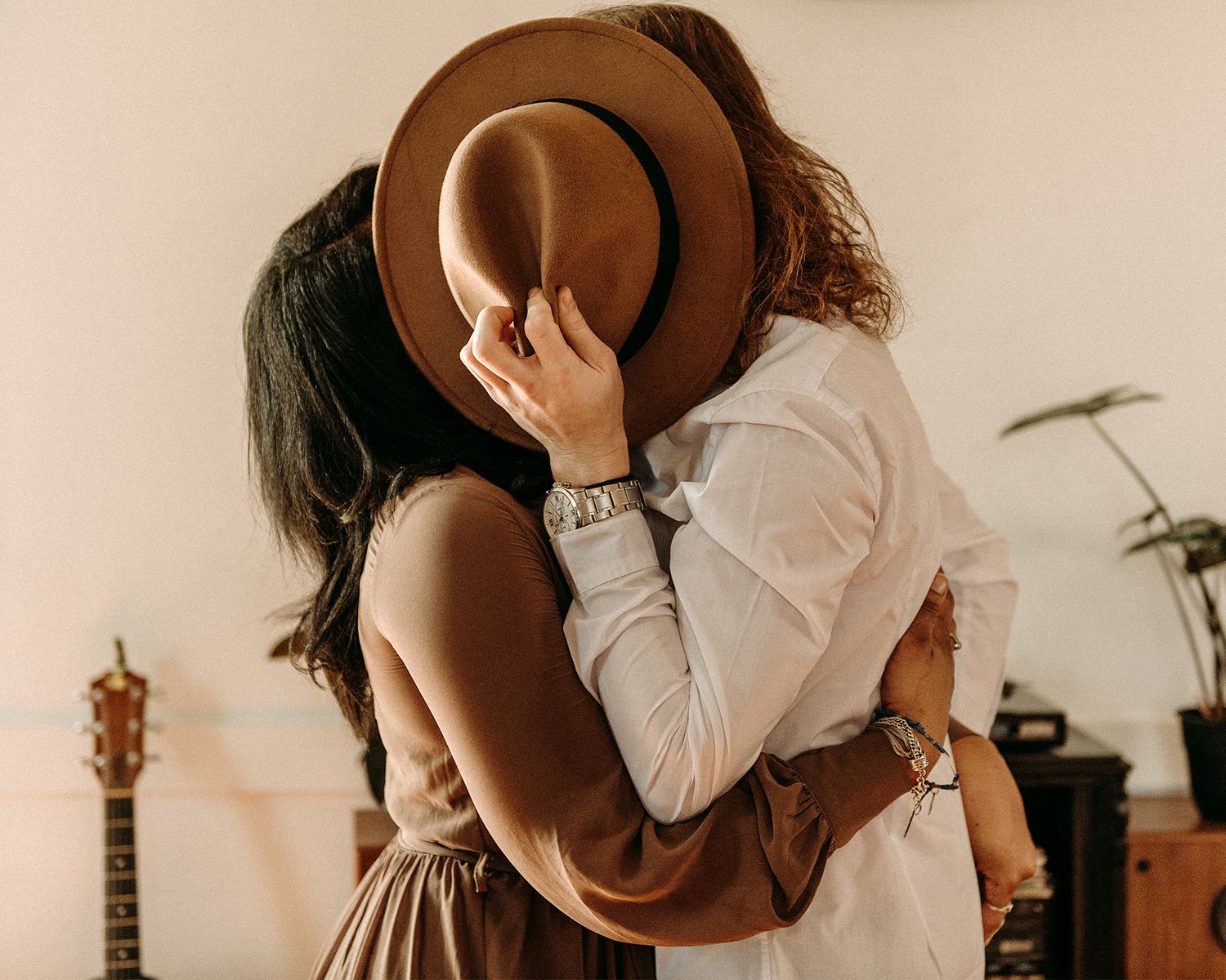 man and woman kissing behind hat