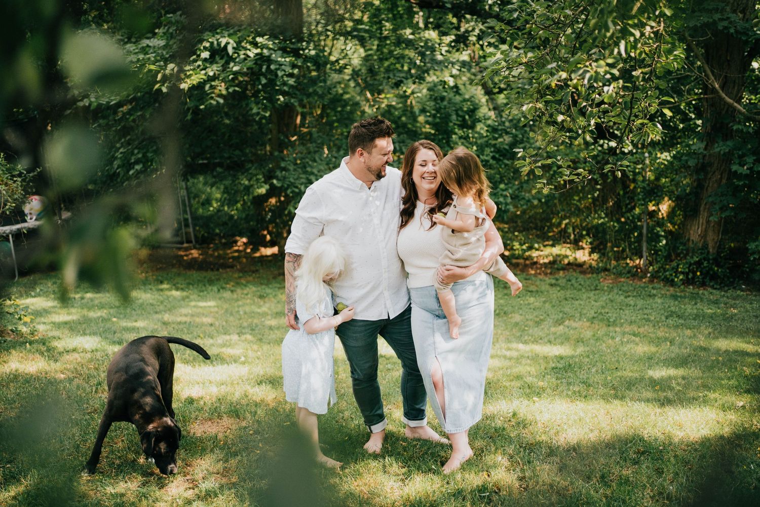 Family enjoying a casual outdoor photo session in a sunlit garden setting.