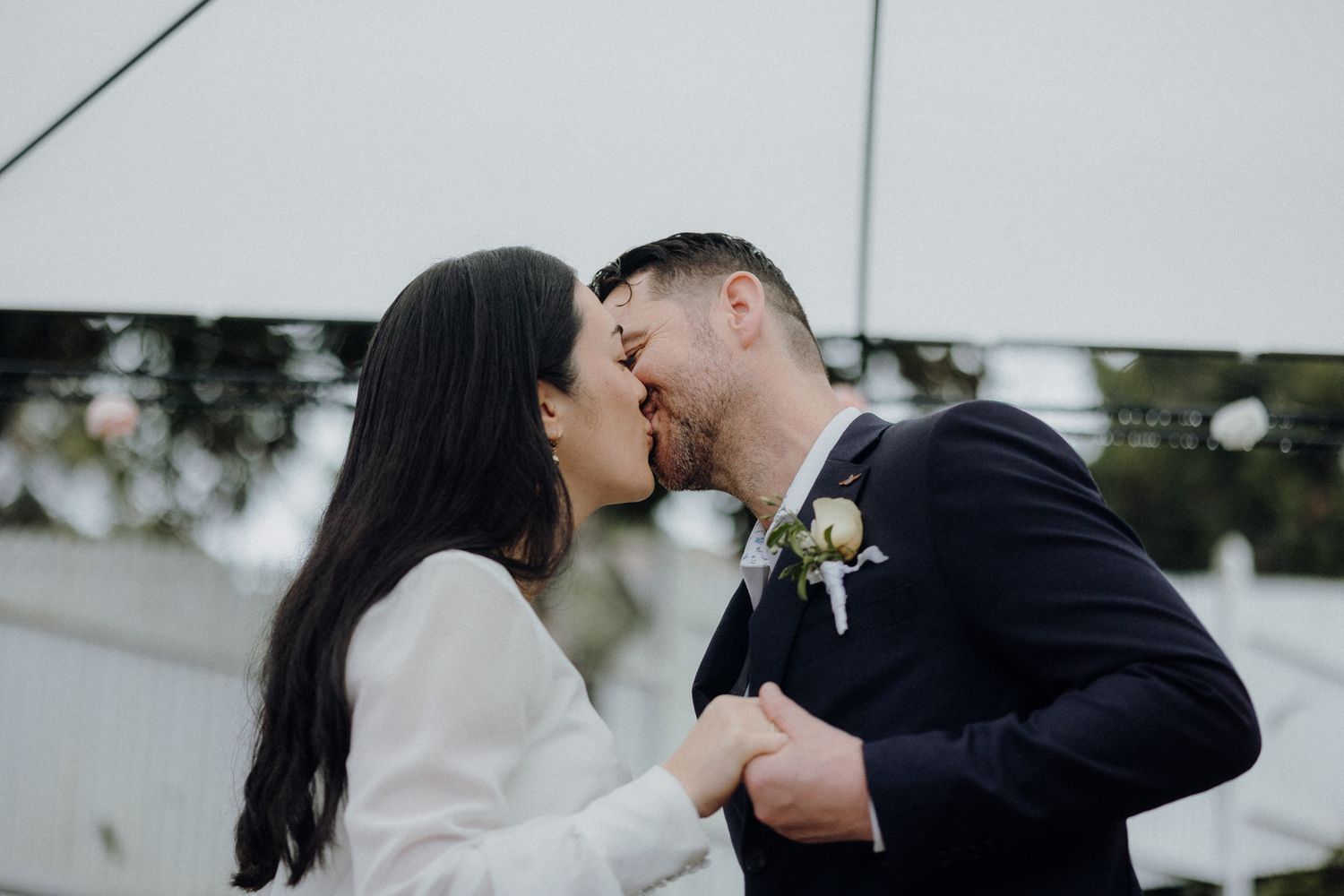 A romantic moment between a couple under soft lighting, with one wearing white and one in navy.
