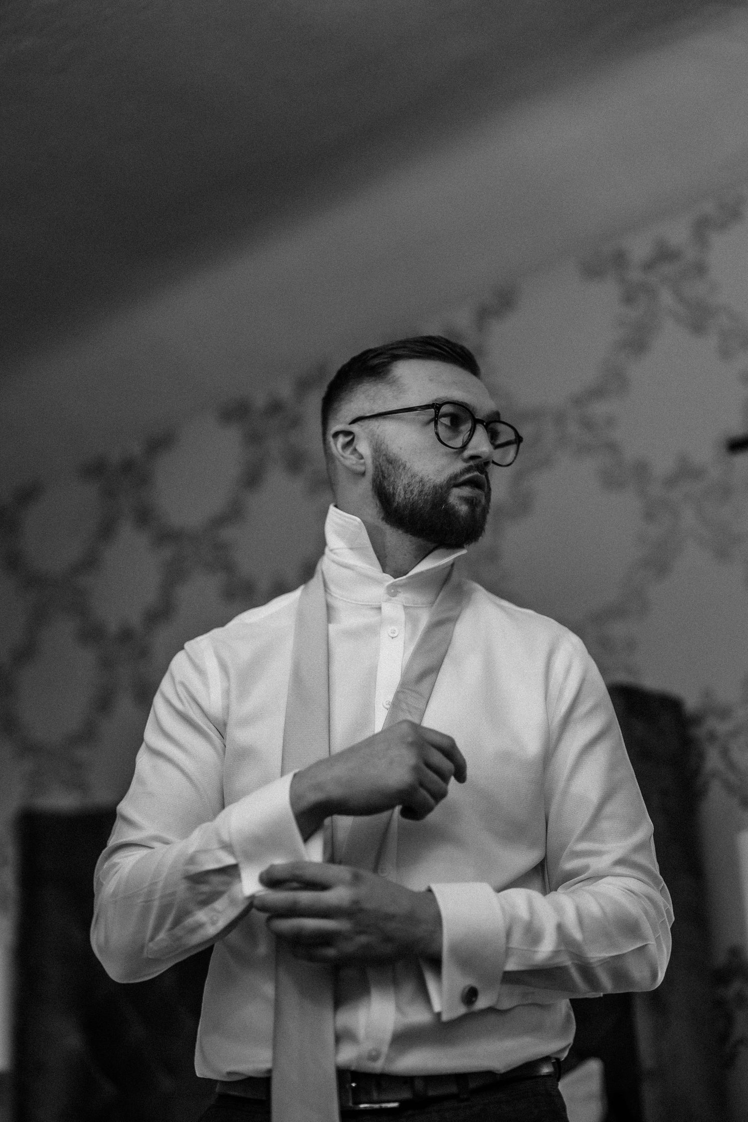 Black and white photo of groom getting ready at wedding in Wales
