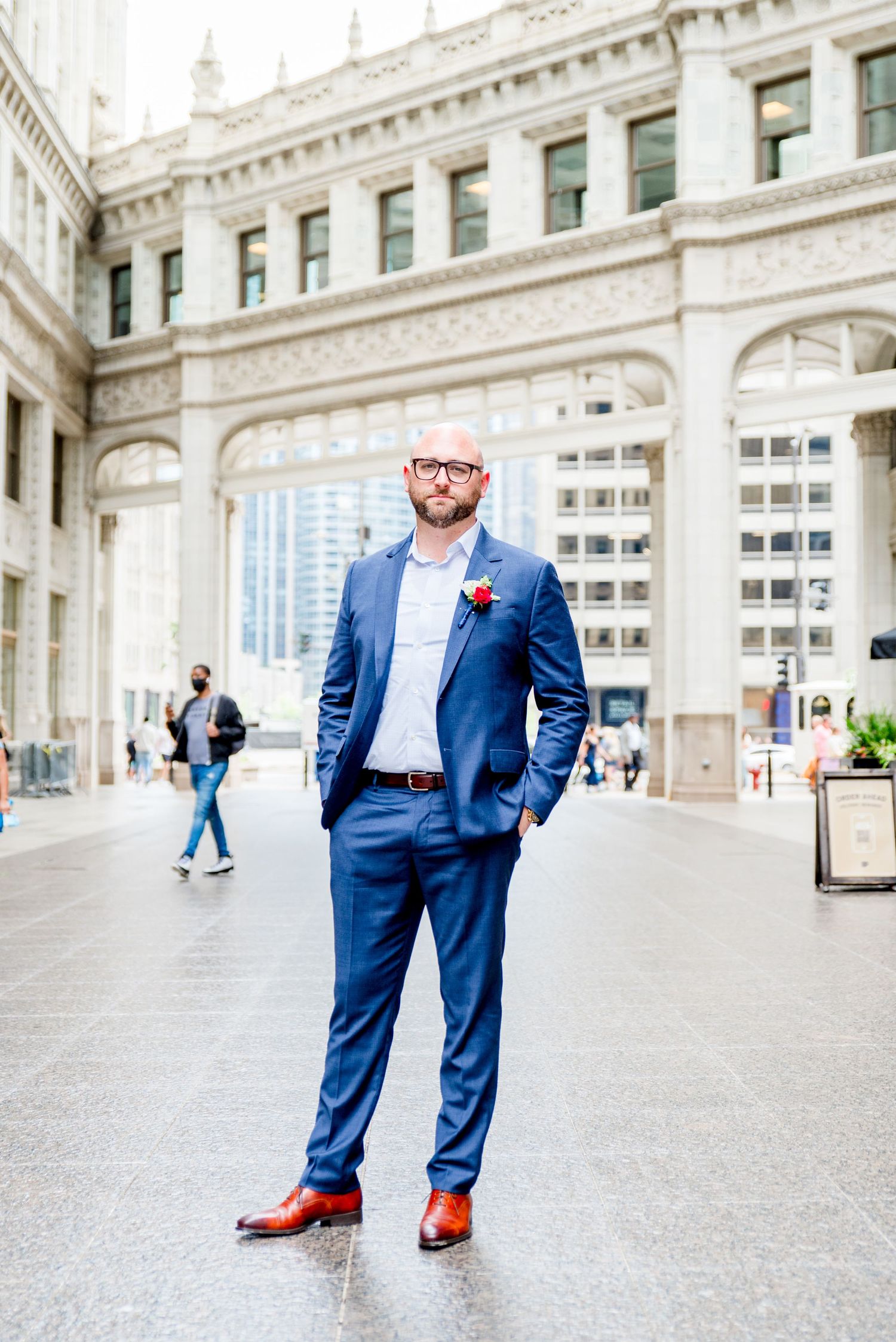 man in navy suit and glasses standing under Wrigley Building Chicago