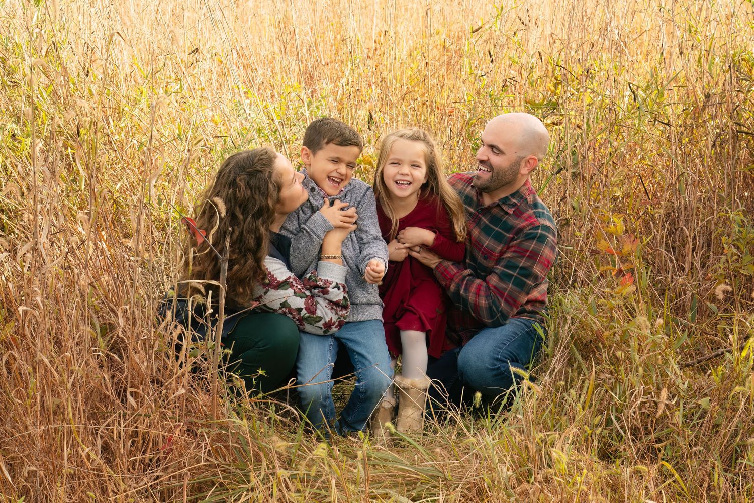 family cuddles in a grassy field at Blandy
