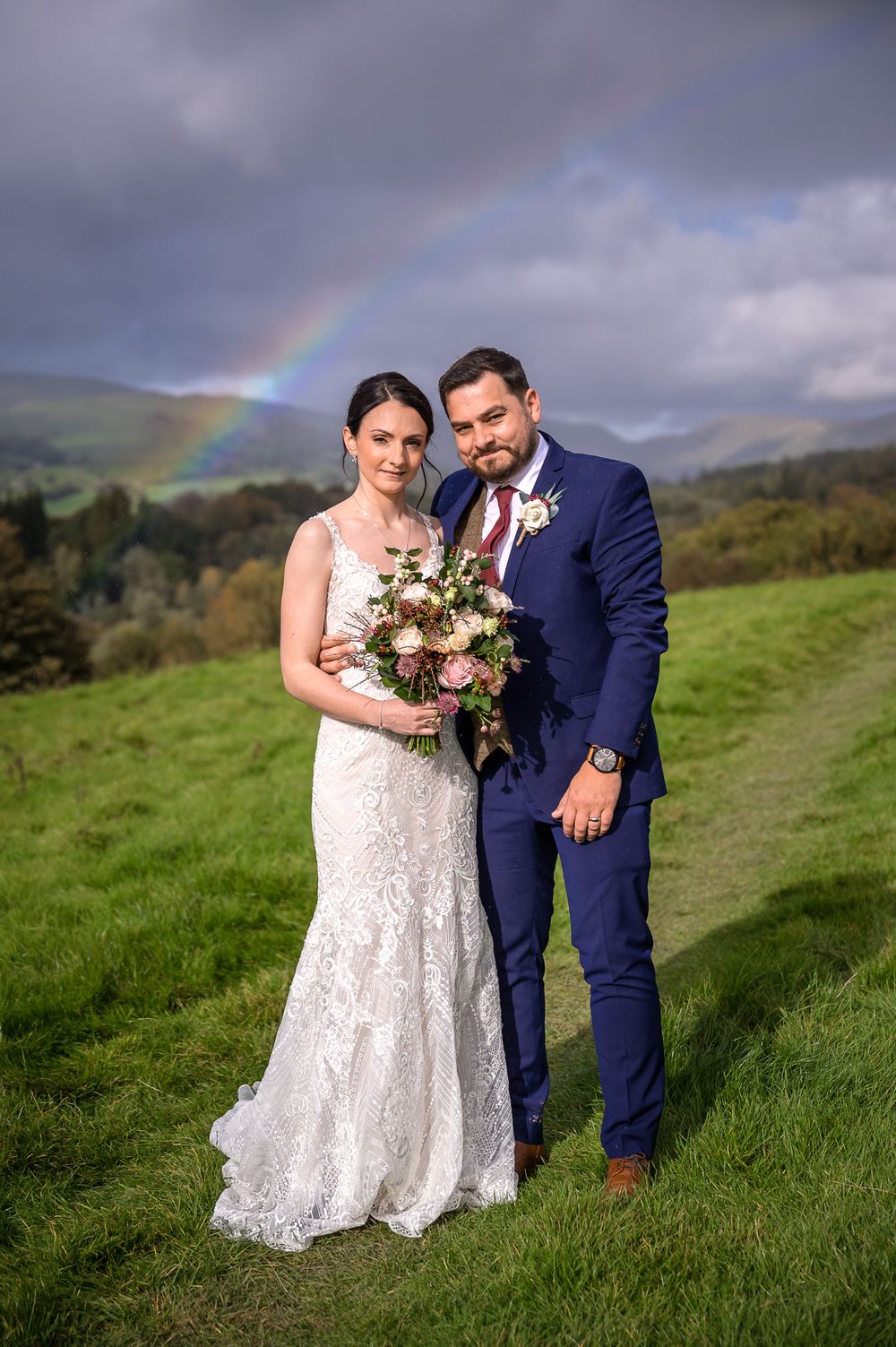 Bride and groom in field with a rainbow