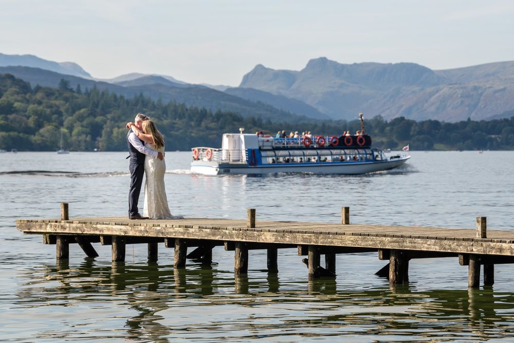Bride and groom on jetty with Windermere launch passing by