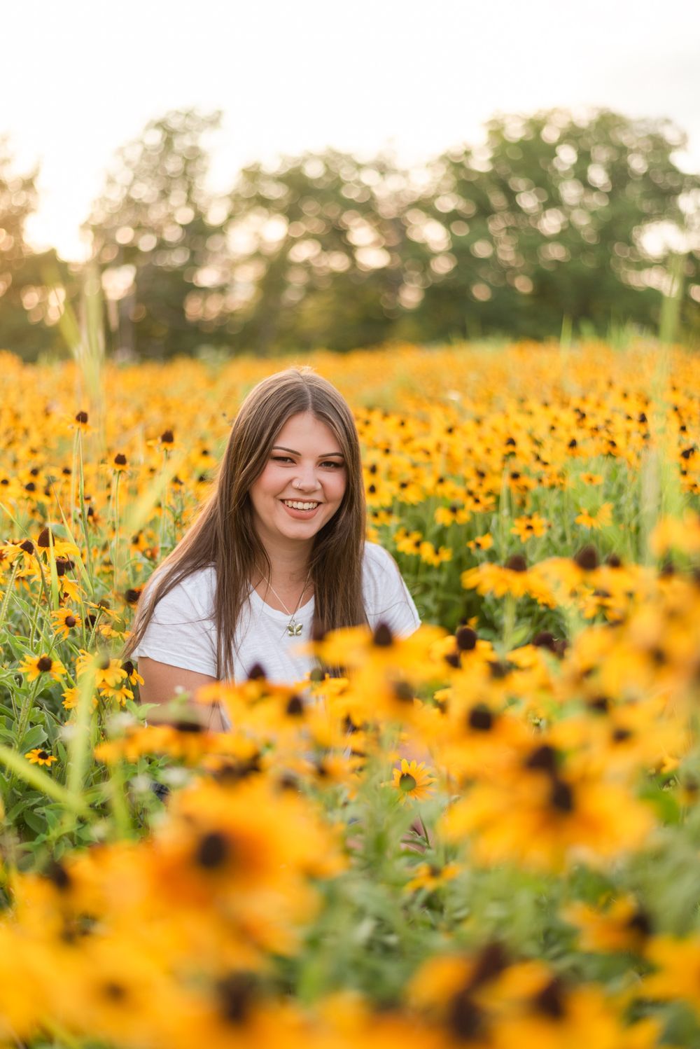 Senior sitting in flower patch in golden sunlight at Hartwood Acres in Pittsburgh Pennsylvania
