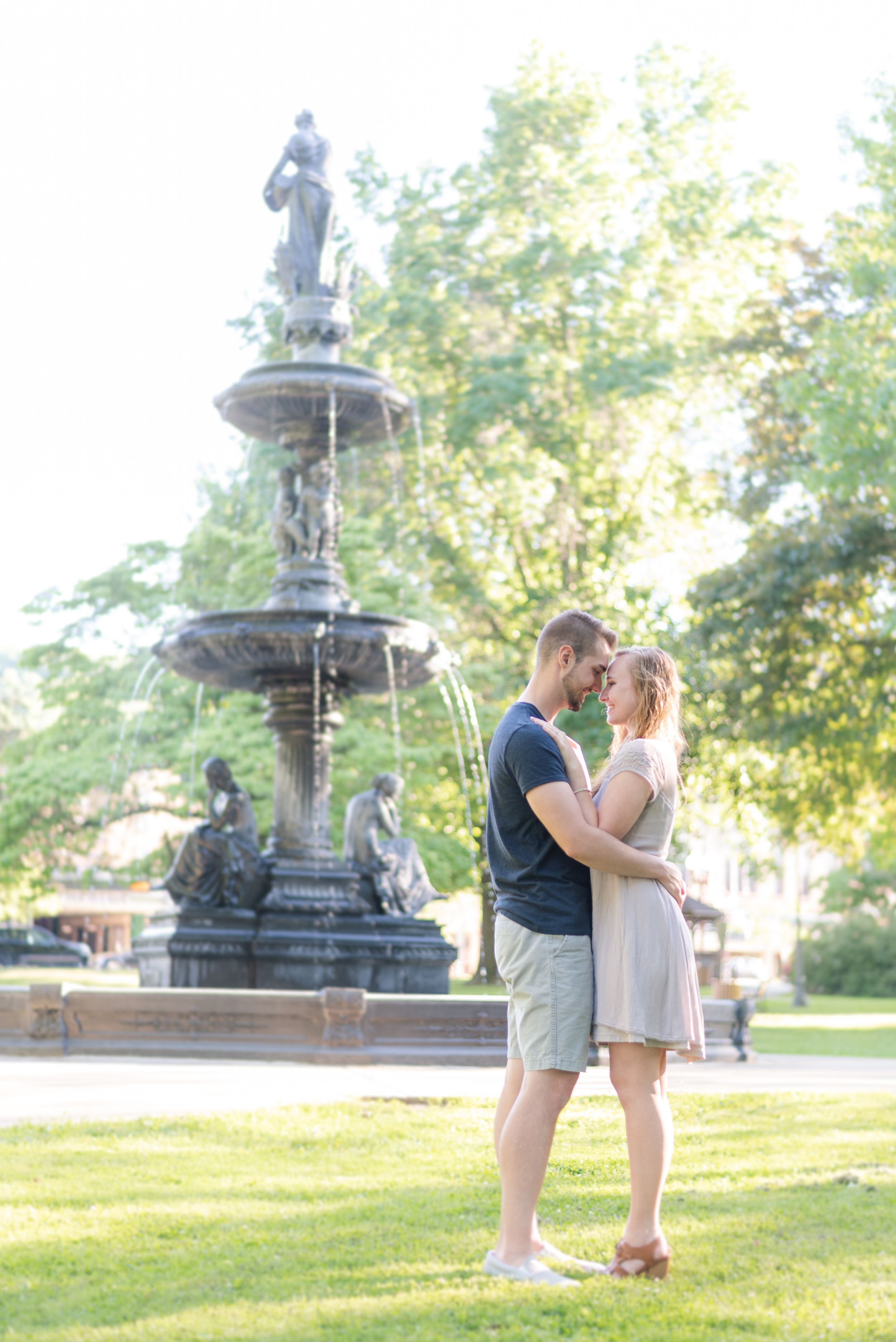 Couple standing in front of fountain in park for engagement in Franklin Pennsylvania