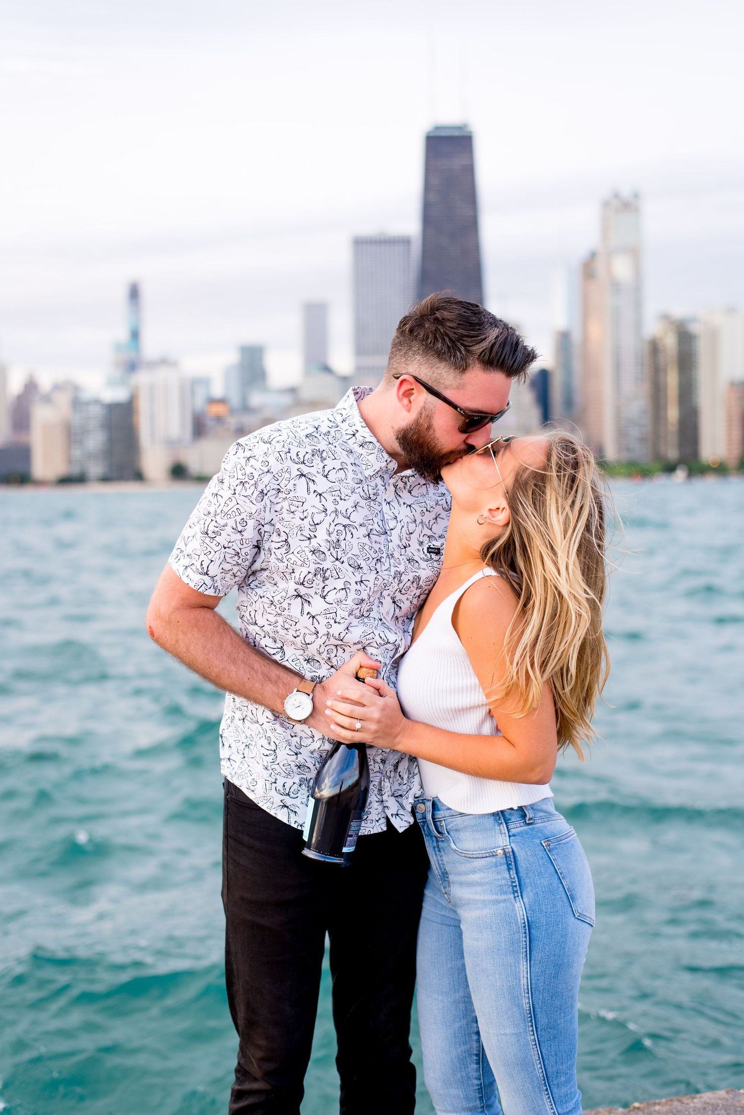 blonde woman in white tank top kisses dark haired man in black and white shirt at North Avenue Beach Chicago pier