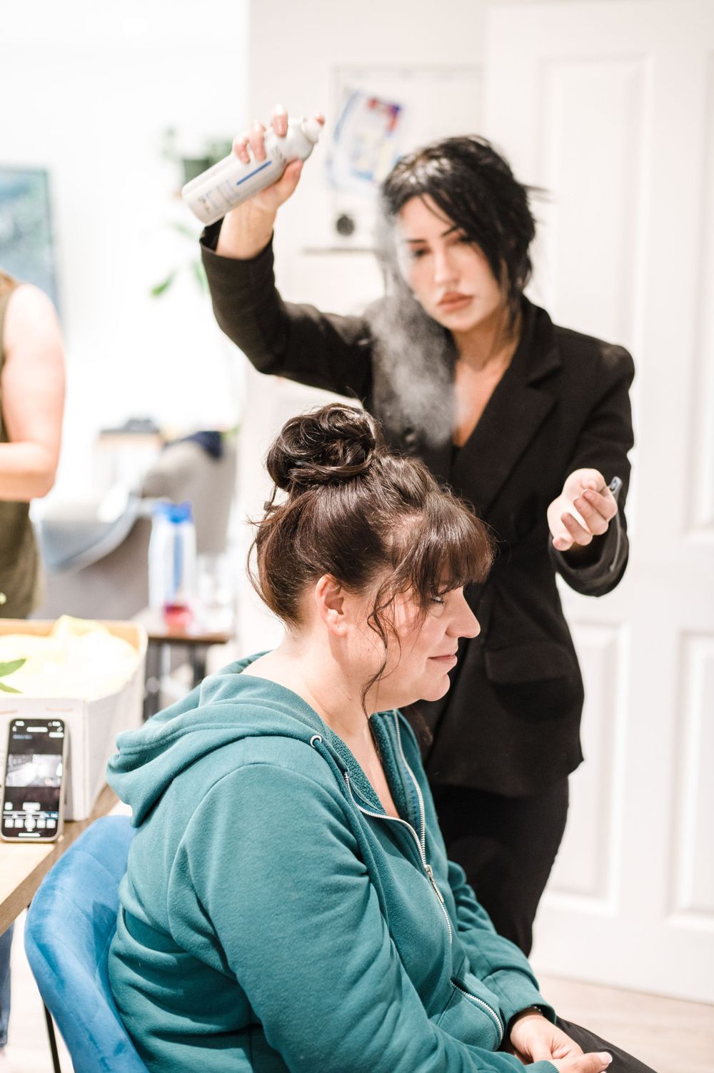 A hair styling session featuring hairspray and updos in a bright indoor setting.