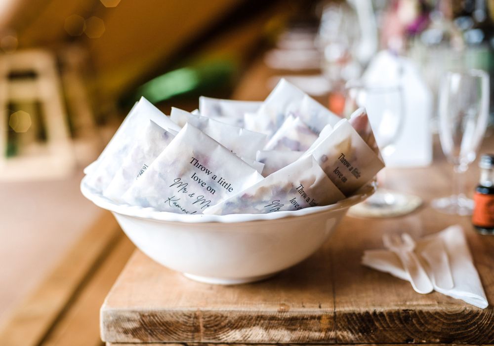 Bowl of white paper wedding favors on rustic wooden surface.