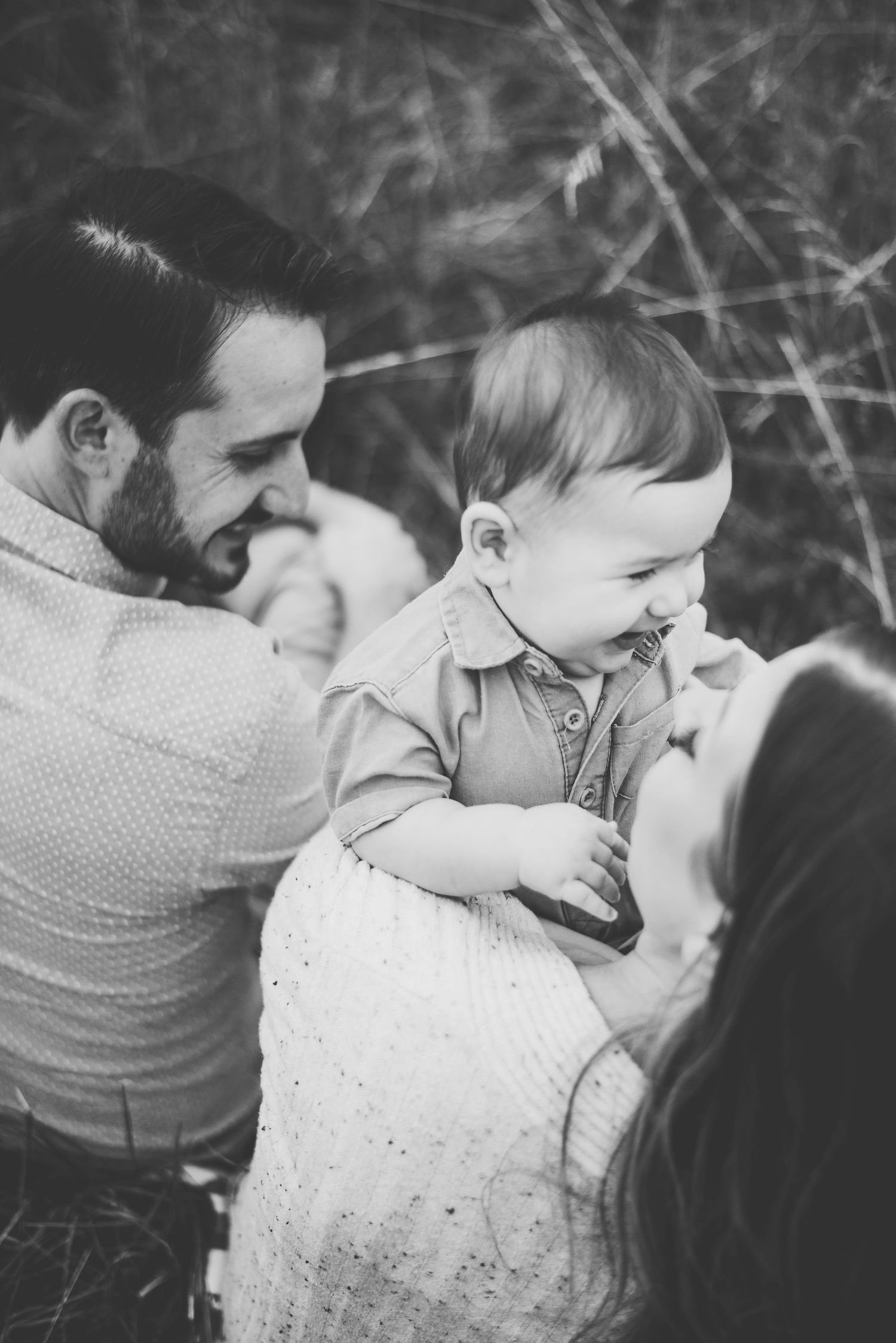 A tender family moment captured in black and white as parents interact with their baby.