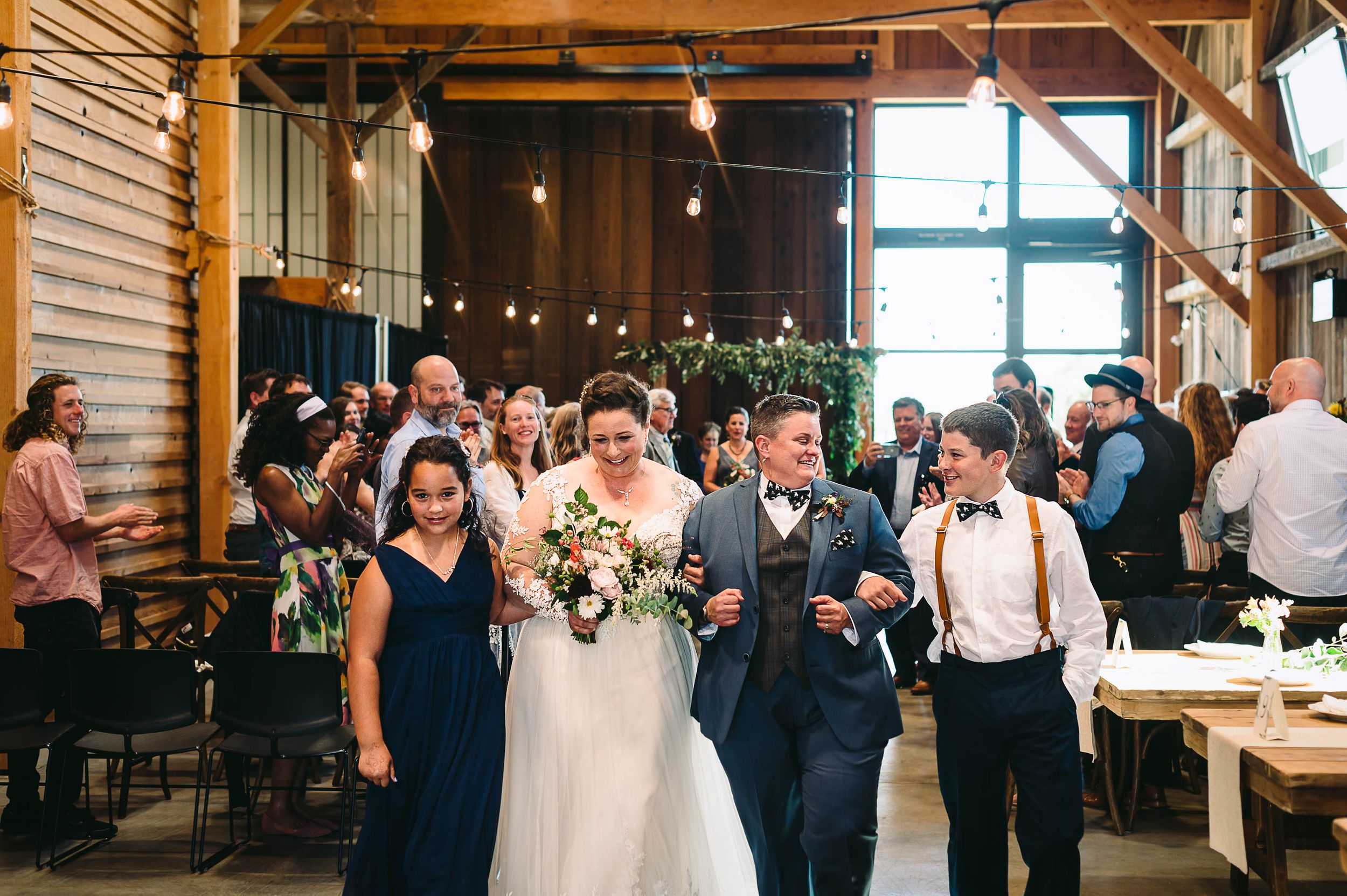 Bride and Bride walking out of the ceremony with their kids