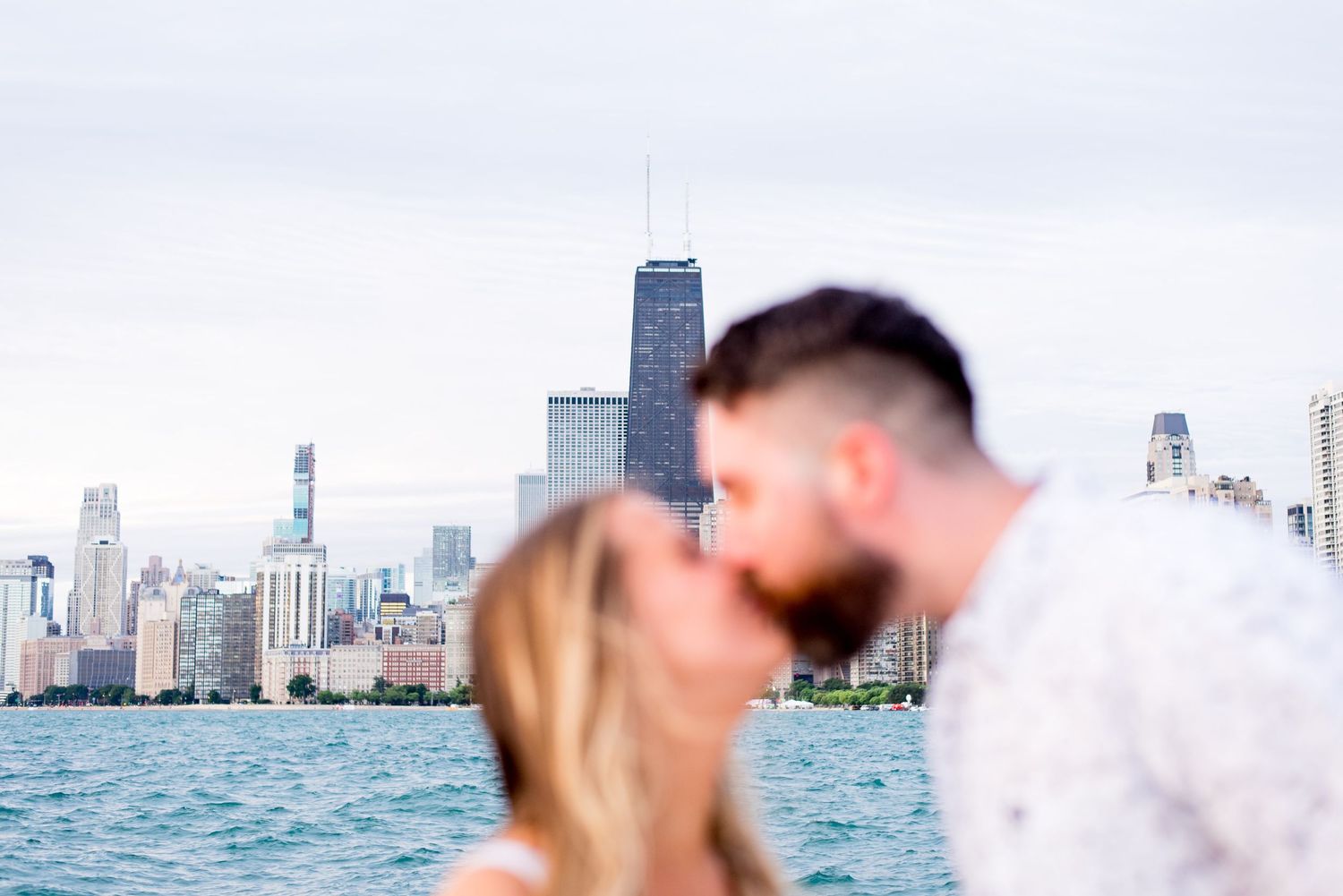 blurry man and woman kiss at North Avenue Beach with the Chicago Skyline in the background