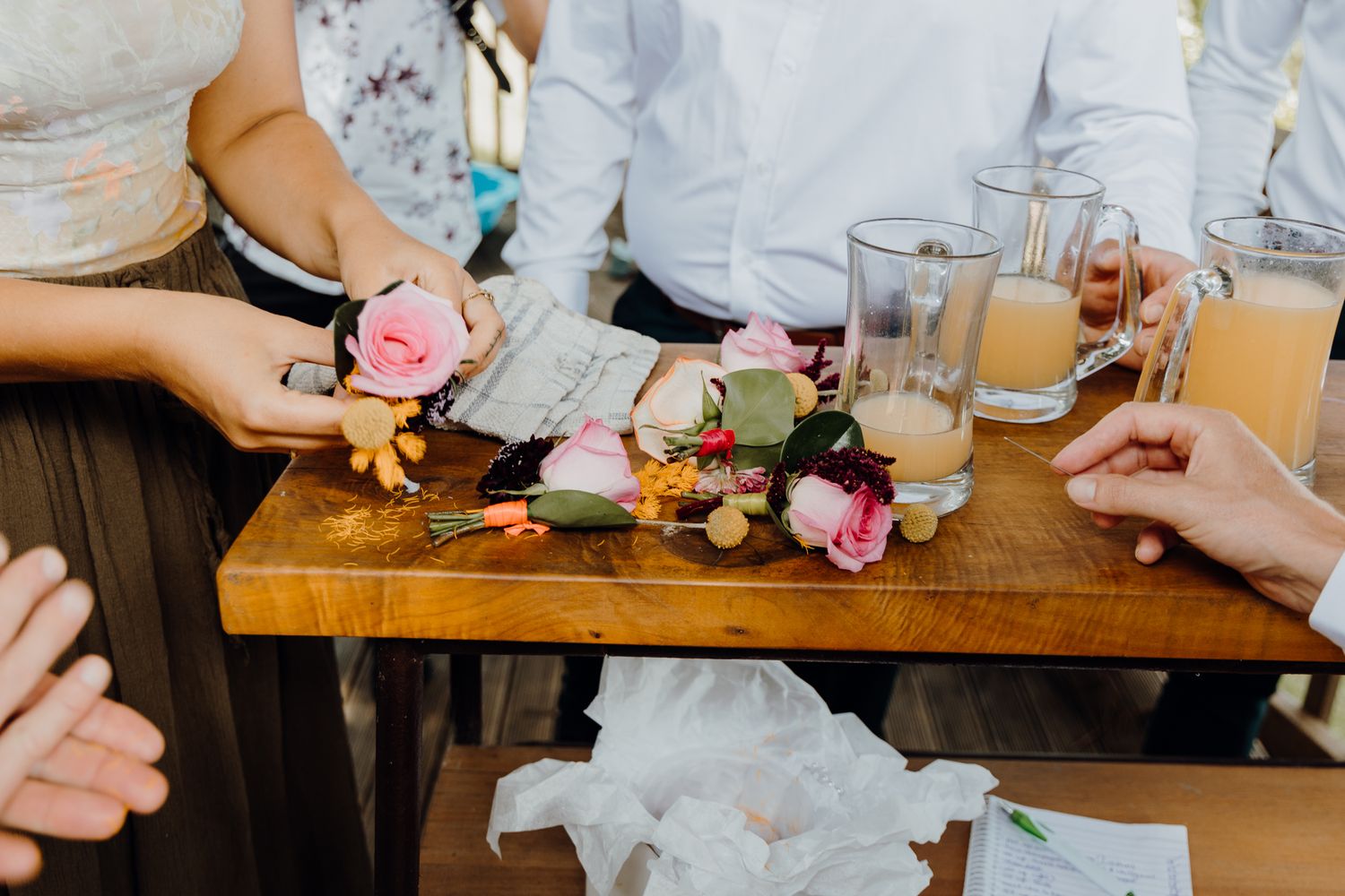 Drinks and floral decorations arranged on a wooden table at an event.